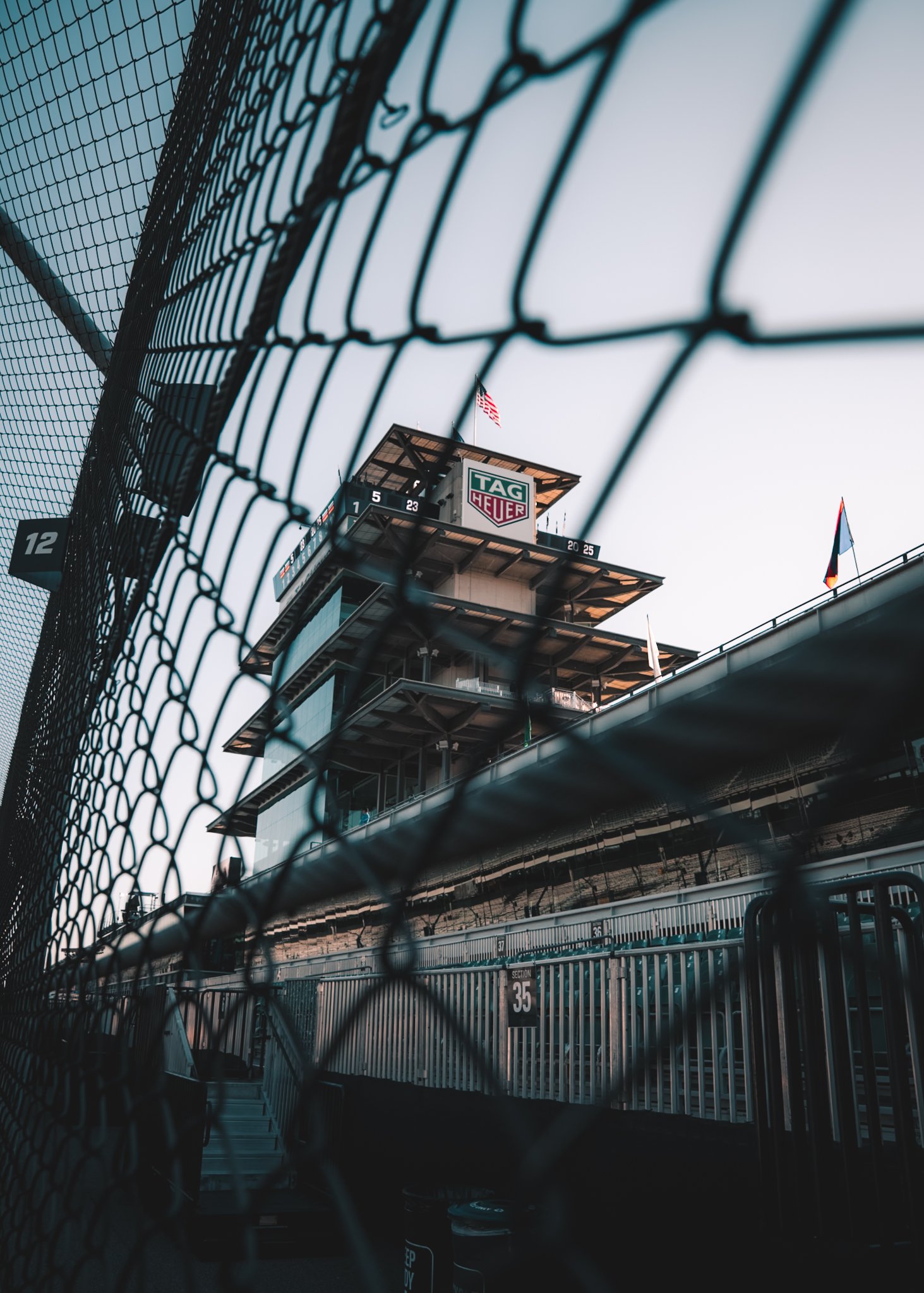 A view of a race track tower behind a chain-link fence at a racing circuit, with the TAG Heuer logo visible on the tower.