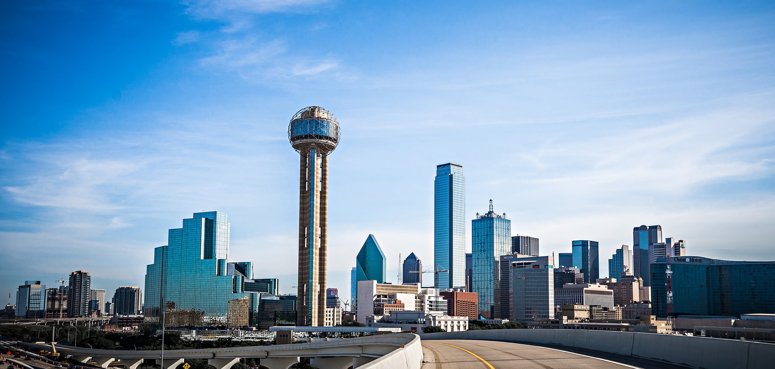 Dallas skyline with Reunion Tower, office buildings, and a clear blue sky.