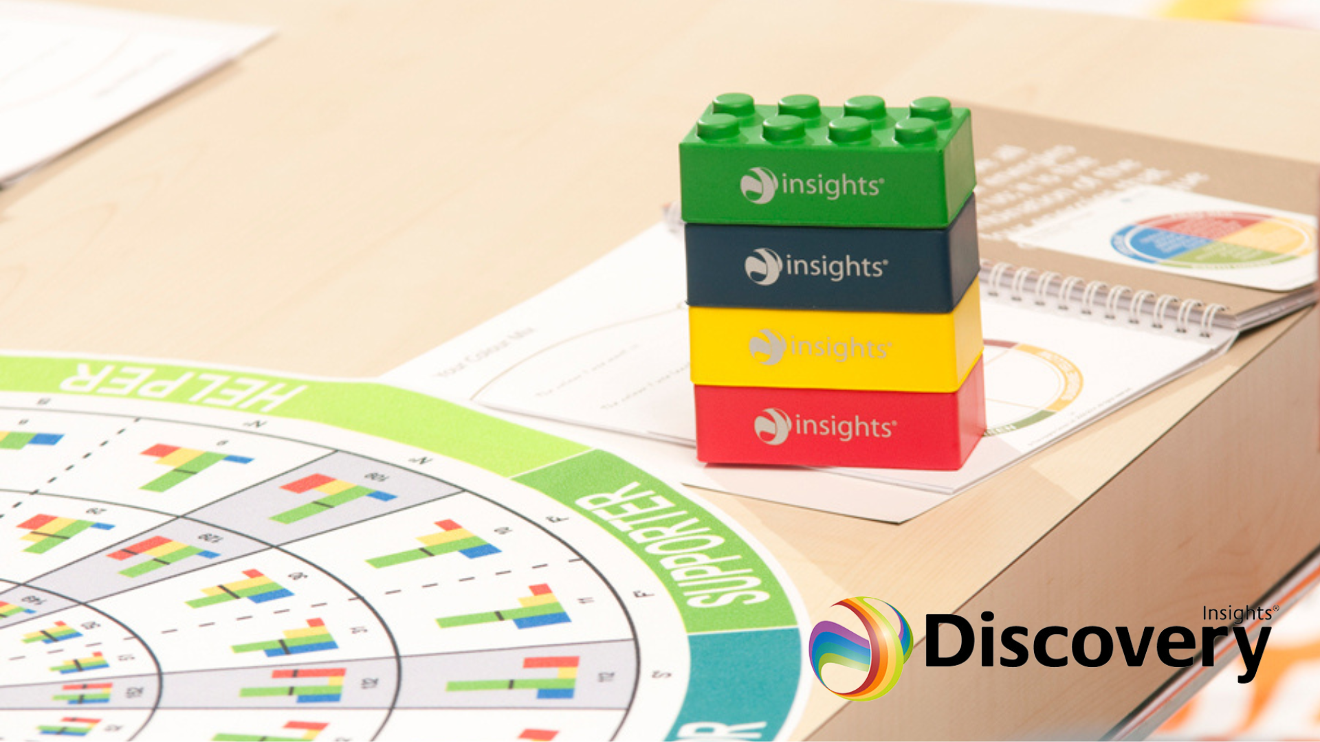 Colored blocks labeled 'insights' stacked on a desk next to a report and a printed chart showing data analysis with a 'REPORT' tab.