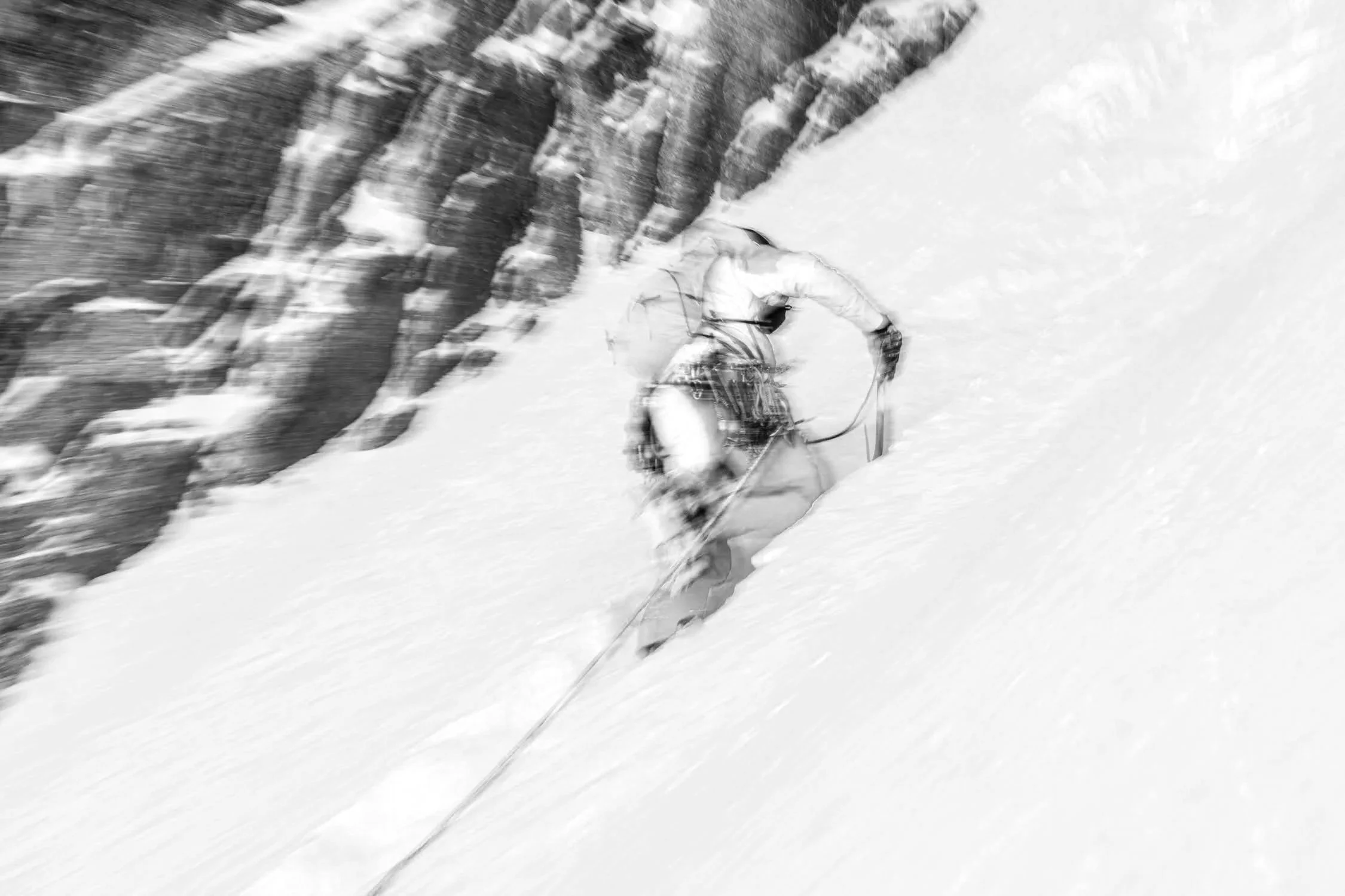 Skieur descendant une pente enneigée près de rochers.
