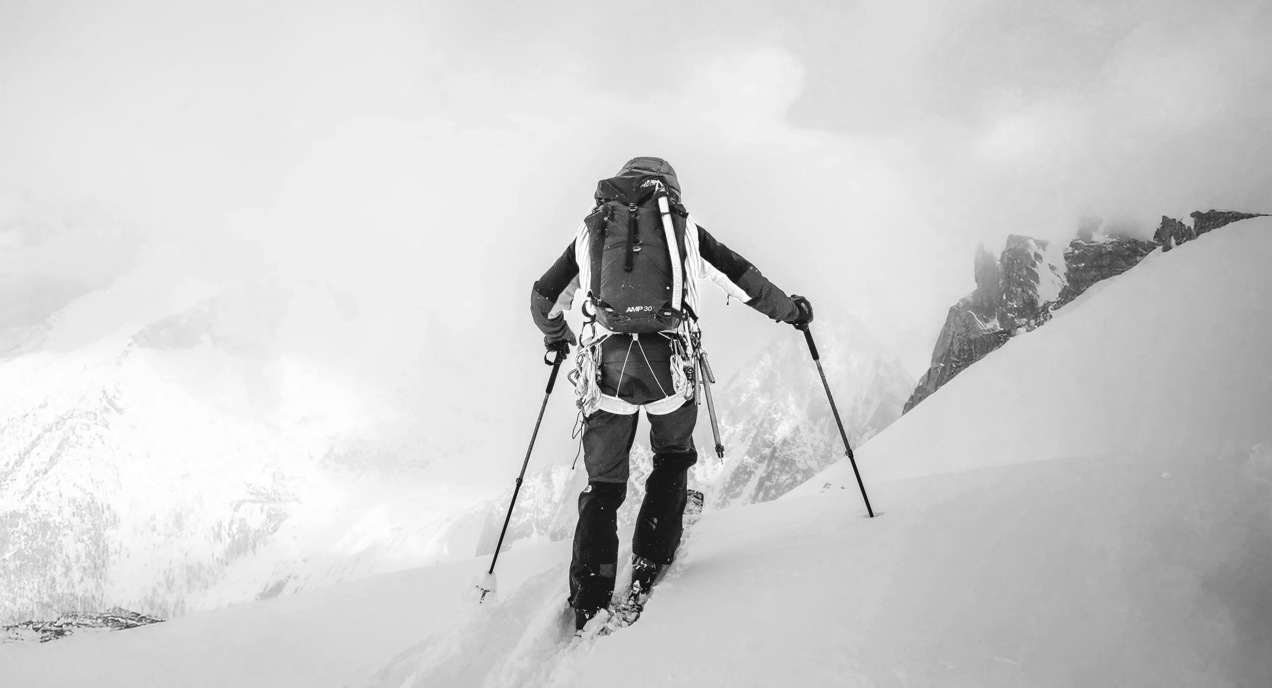 Alpiniste avec sac à dos et bâtons en randonnée dans la neige en montagne.