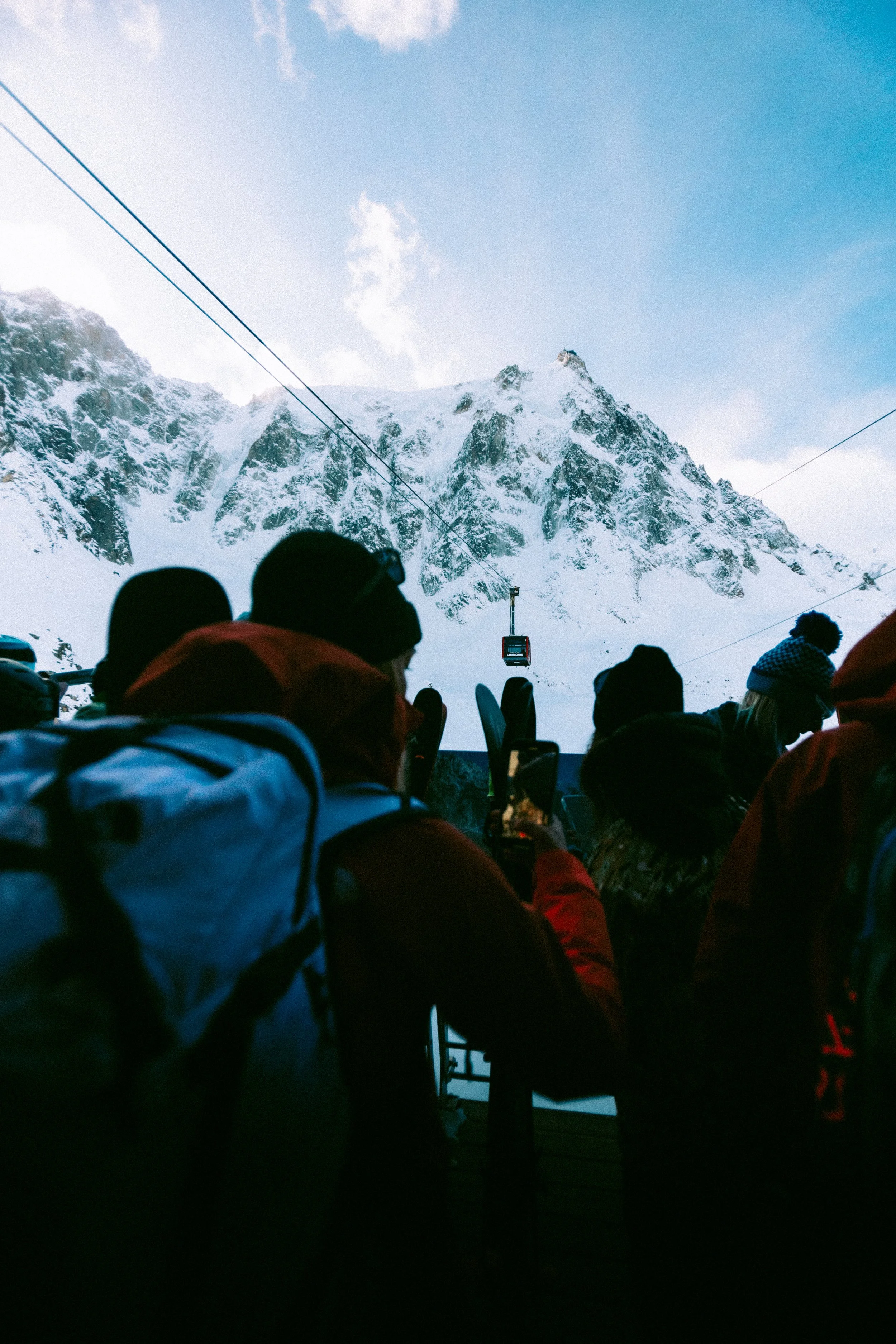 Groupe de personnes dans un tramway ou téléphérique, avec des montagnes enneigées en arrière-plan.