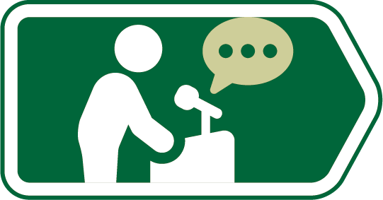 Sign with a person speaking at a podium and a speech bubble.