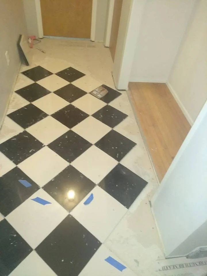 Checked pattern black and white tile installed in a hallway. 