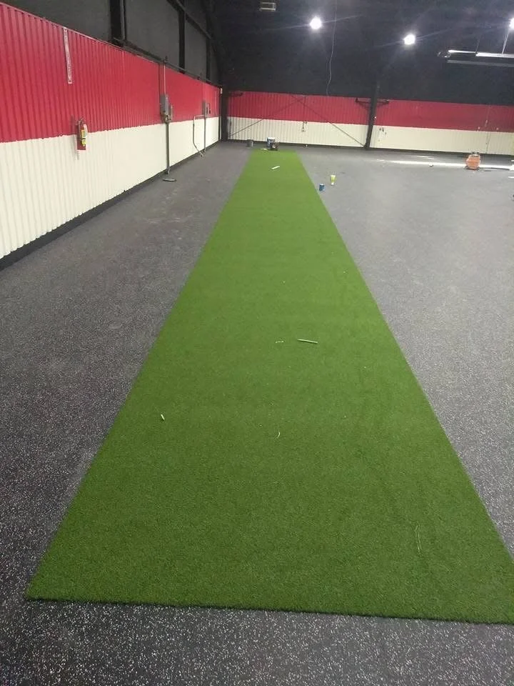 High‑density rubber flooring and a turf strip installed to reduce noise and improve traction in a fitness environment. 

