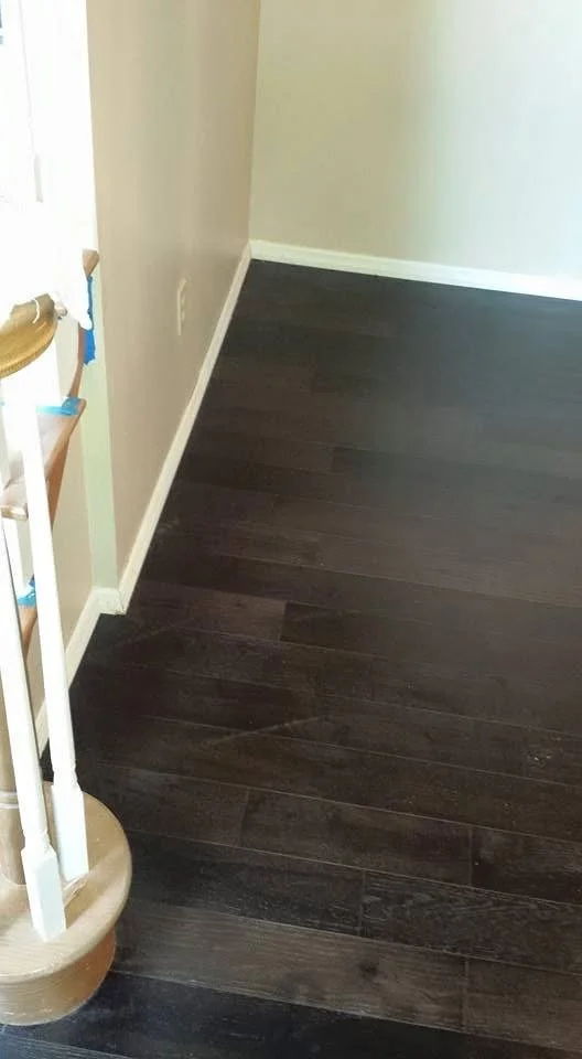Dark-tone hardwood flooring installed with consistent grain alignment and clean edges. 