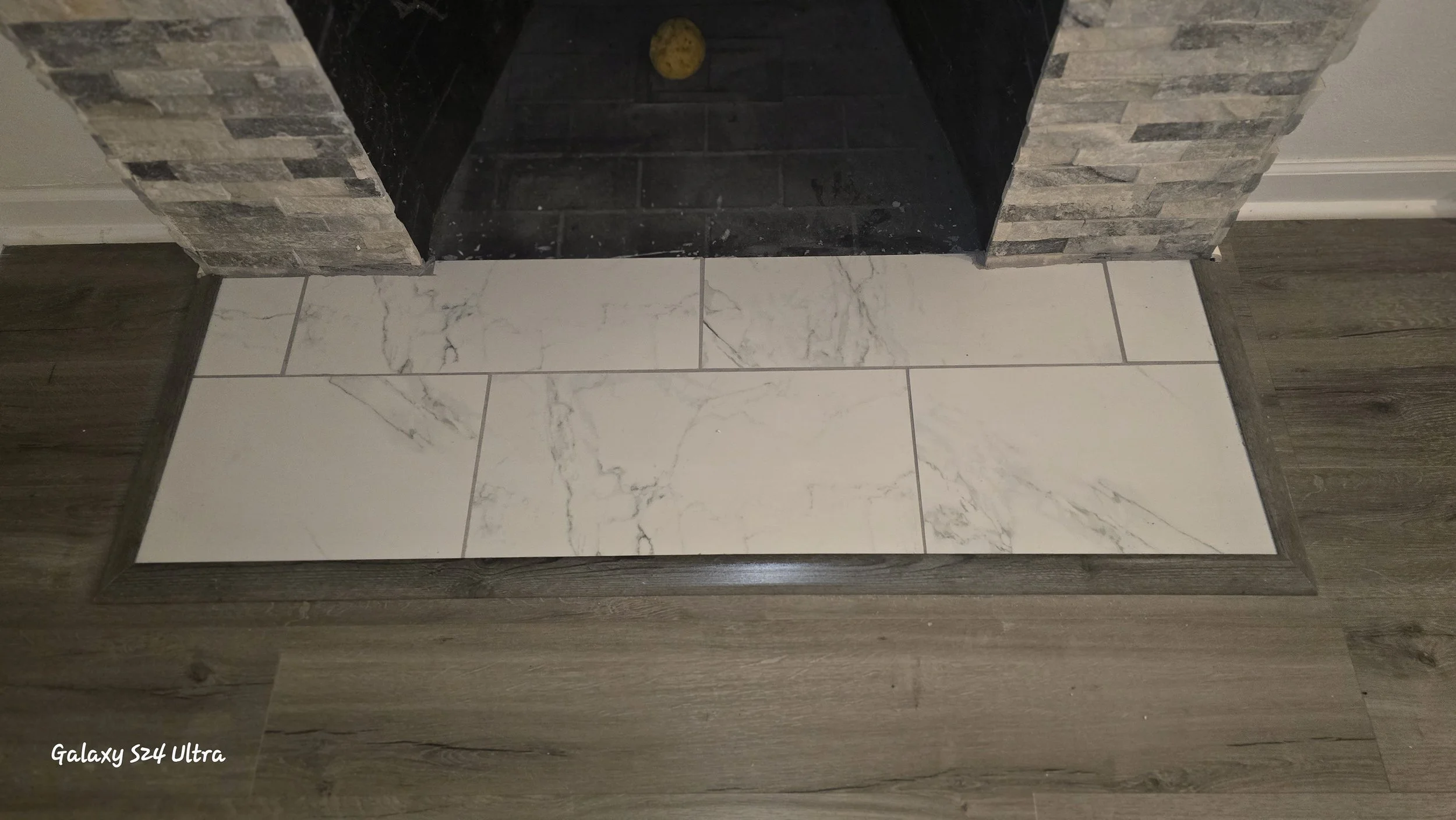 Fireplace with tile installed in front with a transition between two flooring types for a smooth connection. 