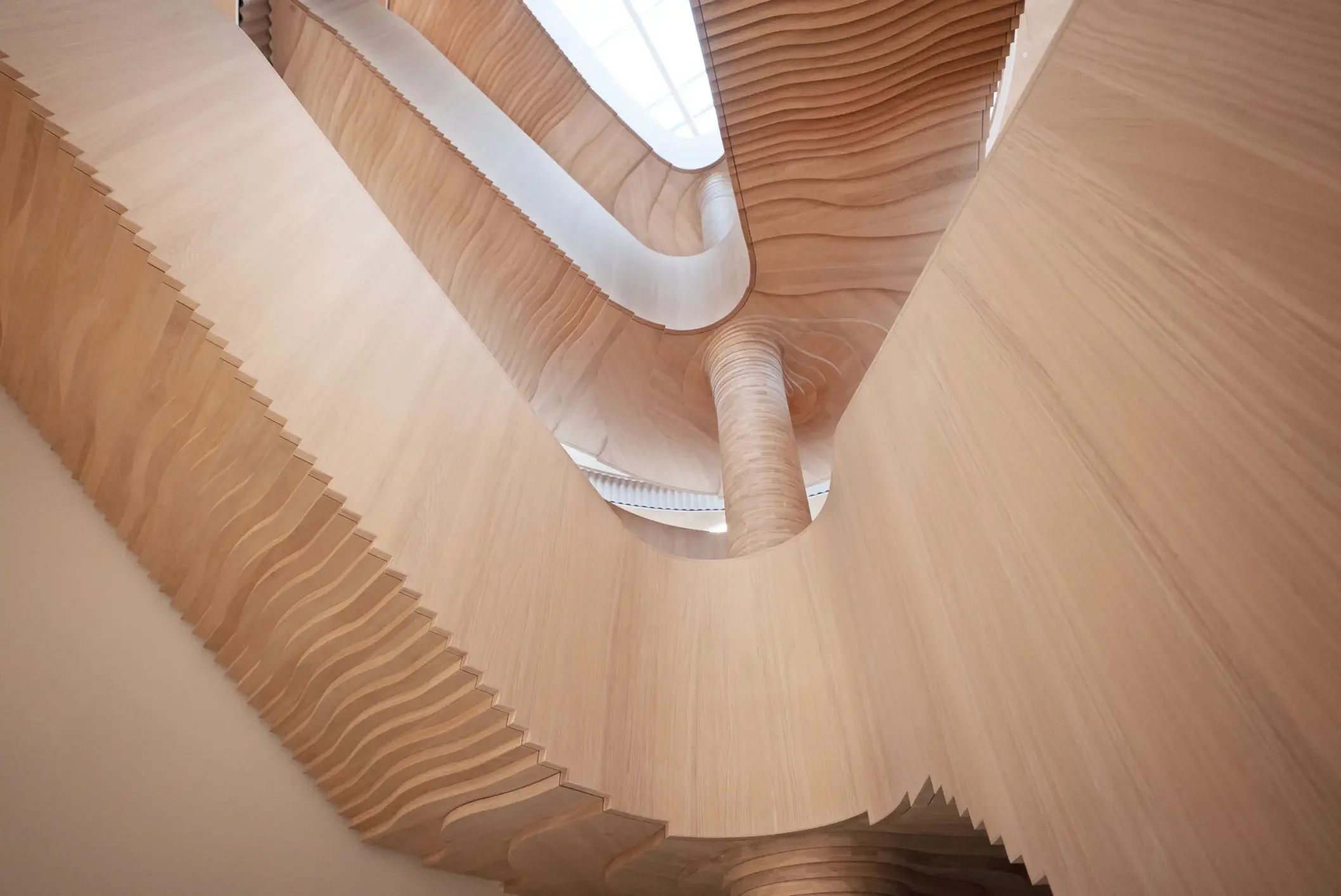 Innvendig spiraltrapp med treverk, sett ovenfra, med en åpen skylight i midten.