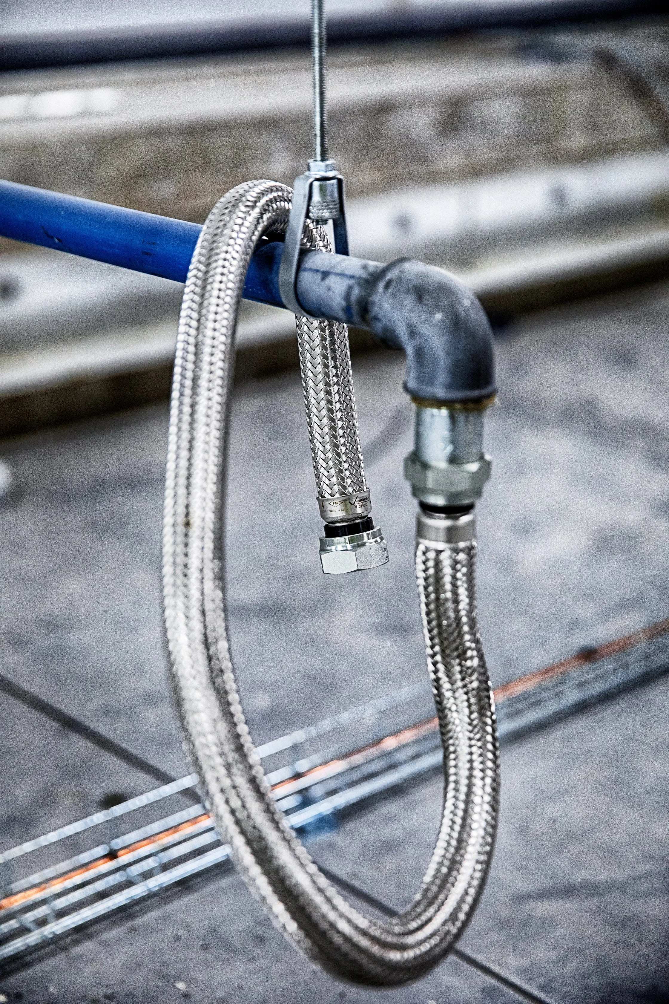 Nærbilde av metallslanger og koblinger som er festet til en gummikobling på et rør.