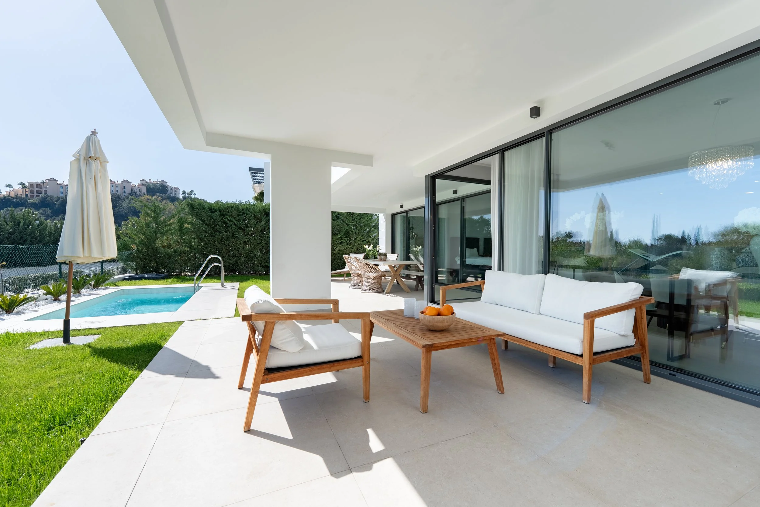 Modern backyard patio with outdoor seating, small pool, and landscaped garden, overlooking hillside homes.