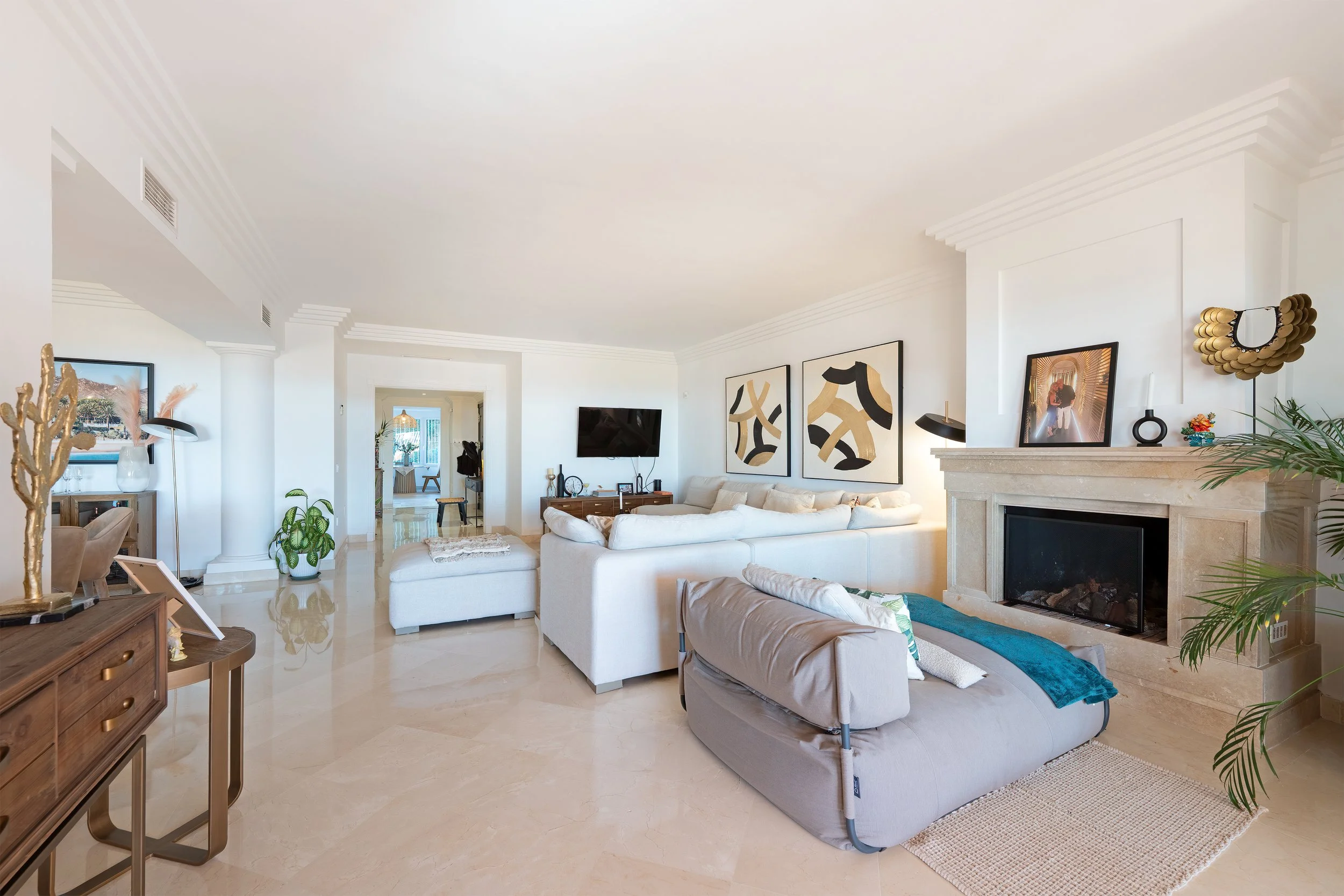 Living room with white walls, beige marble floors, modern furniture, artwork, and decorative items.