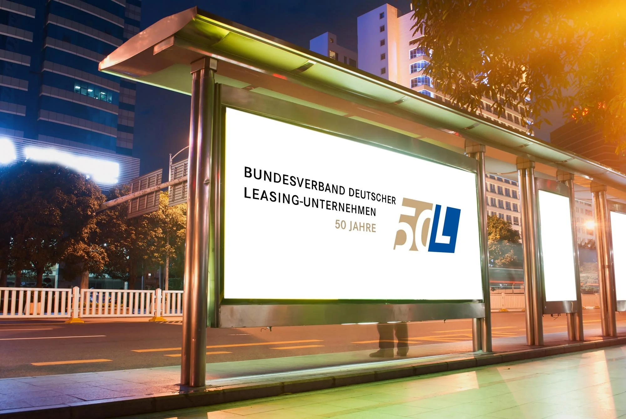 Werbetafel an Bushaltestelle mit Logo und Text für den Bundesverband Deutscher Leasing-Unternehmen, 50 Jahre, in einer Stadt bei Nacht