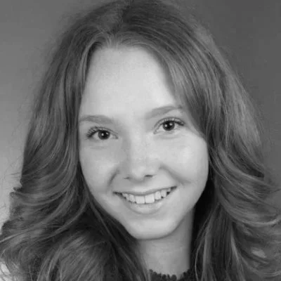 Schwarz-weiß Porträt eines lächelnden jungen Mädchens mit langen, gewellten Haaren.