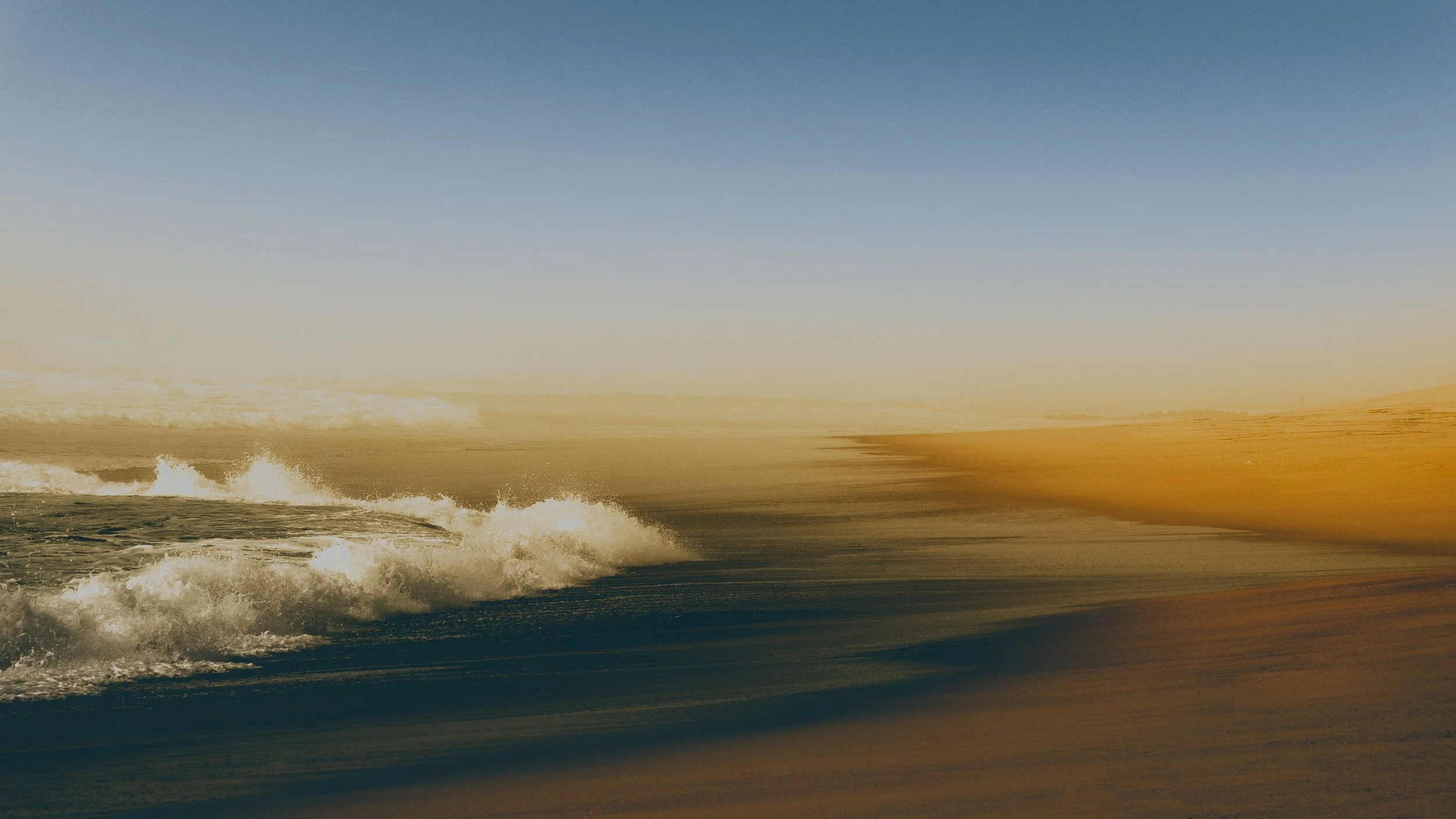 Vue d'une plage avec des vagues et un ciel clair, le paysage semble déformé par un effet artistique.