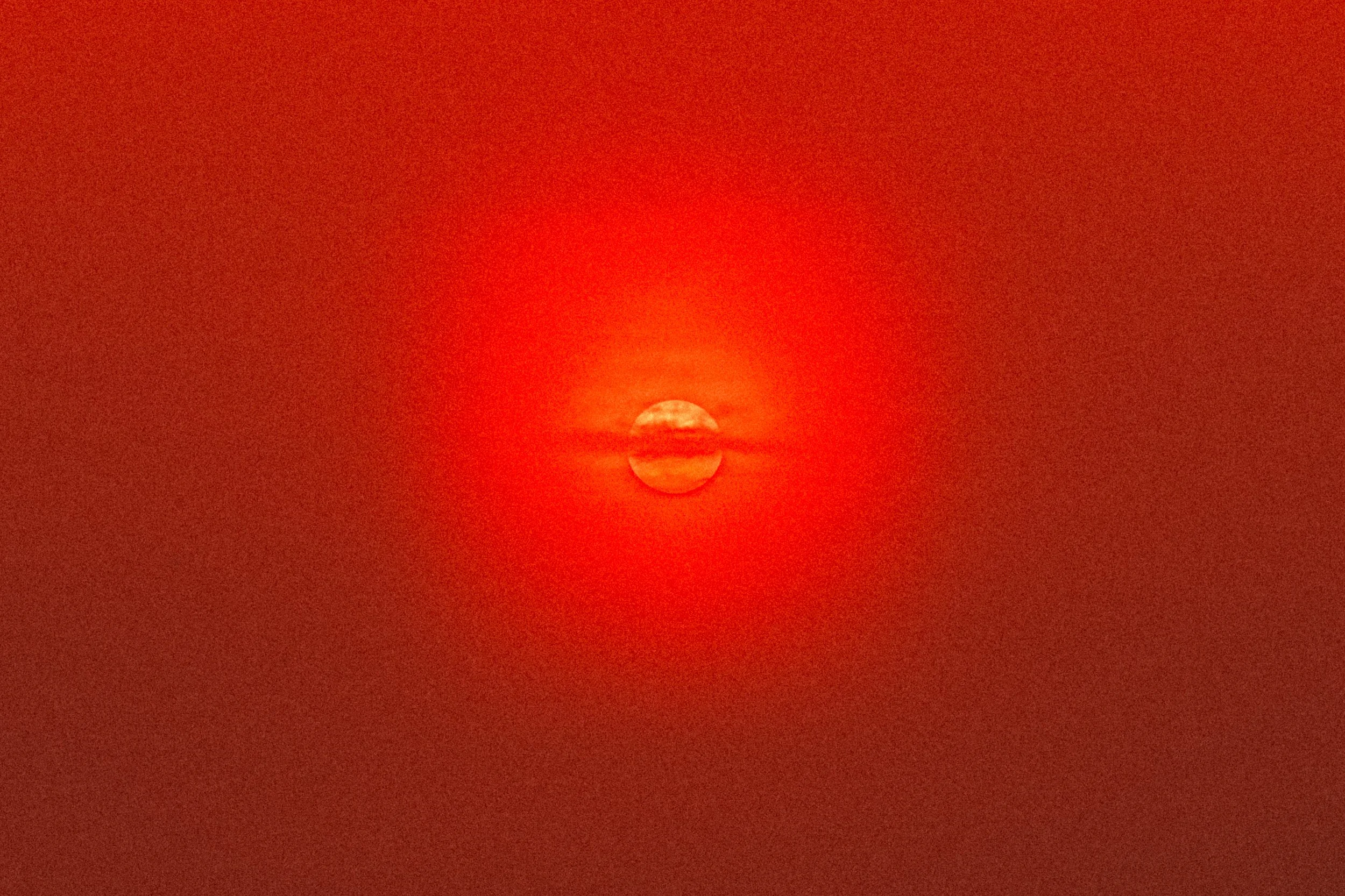 Le soleil rougeâtre à l'horizon lors d'un coucher ou lever de soleil avec un ciel rouge intense