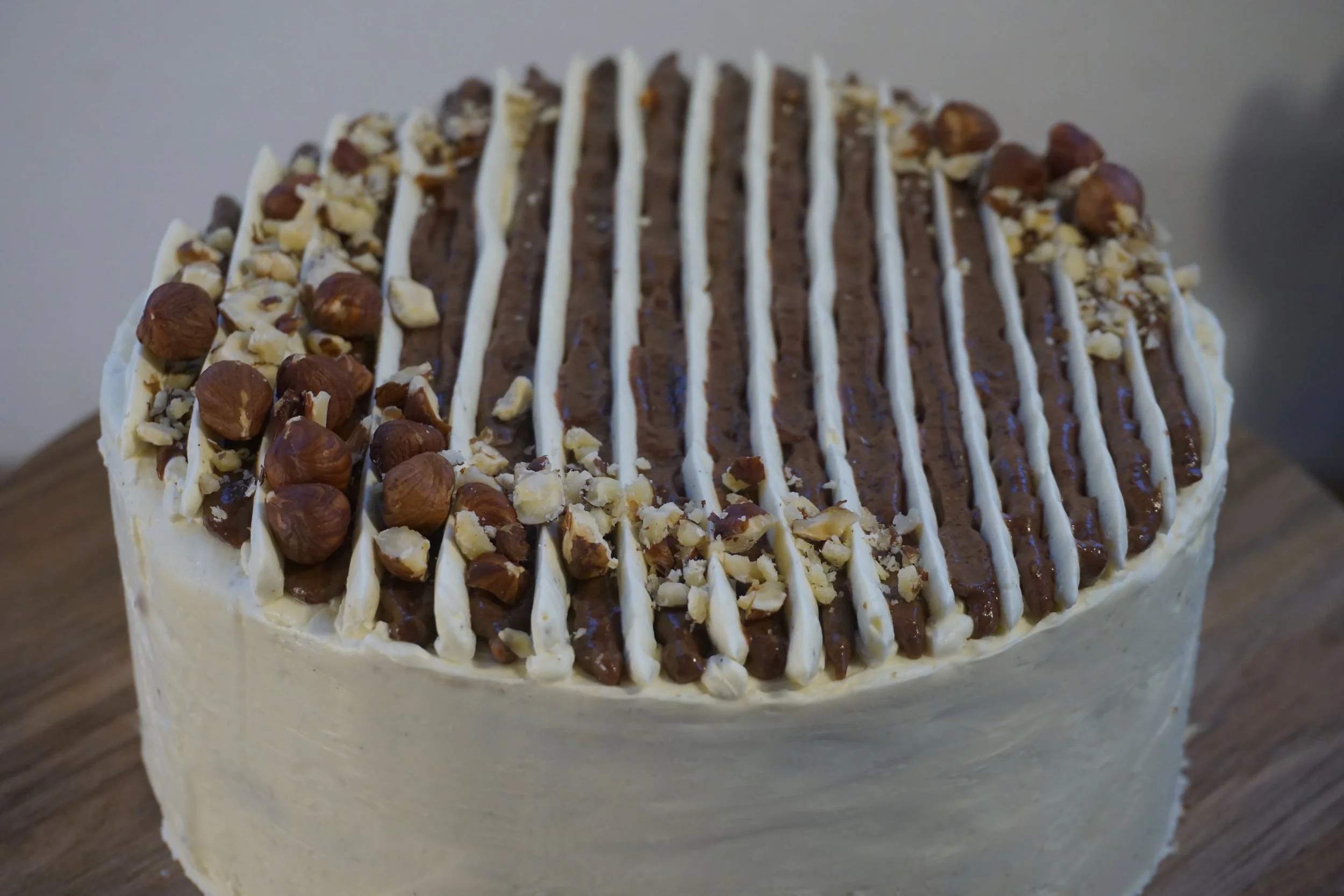 weiße Cremetorte Streifendekor und Nüssen