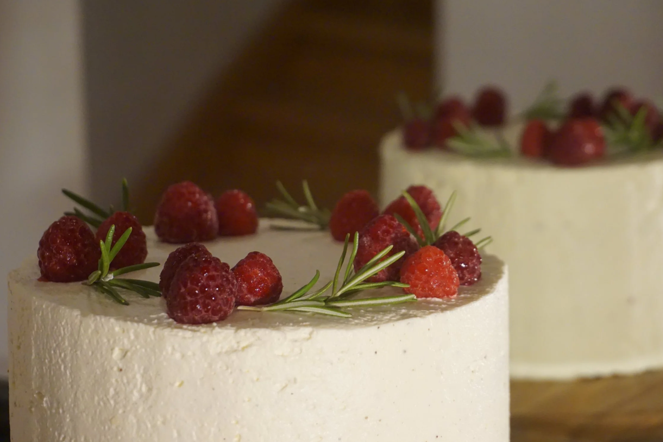 Weiße Torten mit gefrorenen Himbeeren und Rosmarin auf der Oberseite