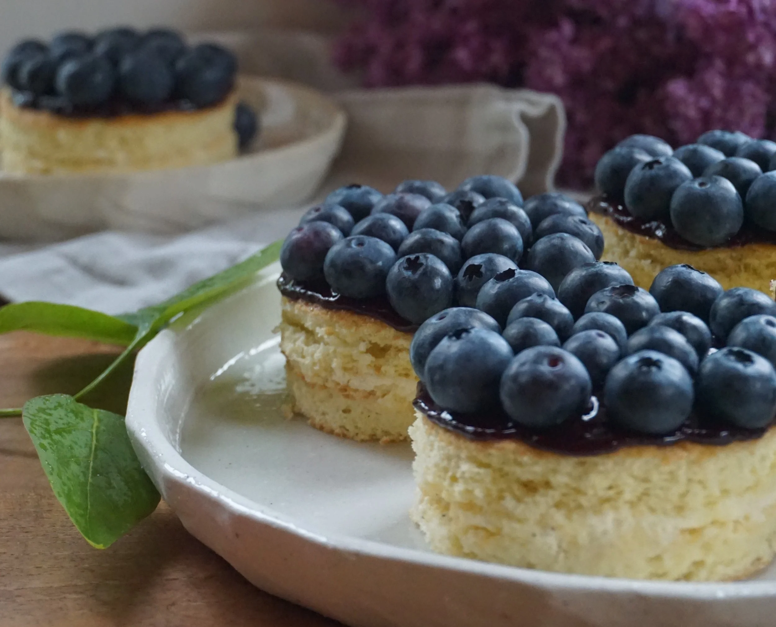 kleine Törtchen mit Blaubeeren, Flieder im Hintergrund