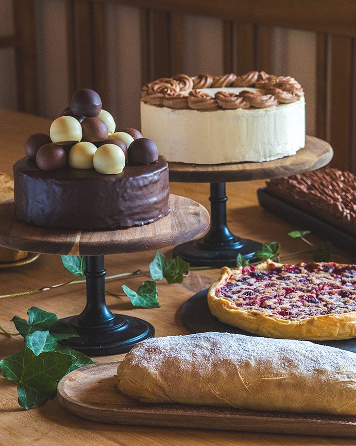 Verschiedene Kuchen und ein Hefezopf auf einem Holztisch