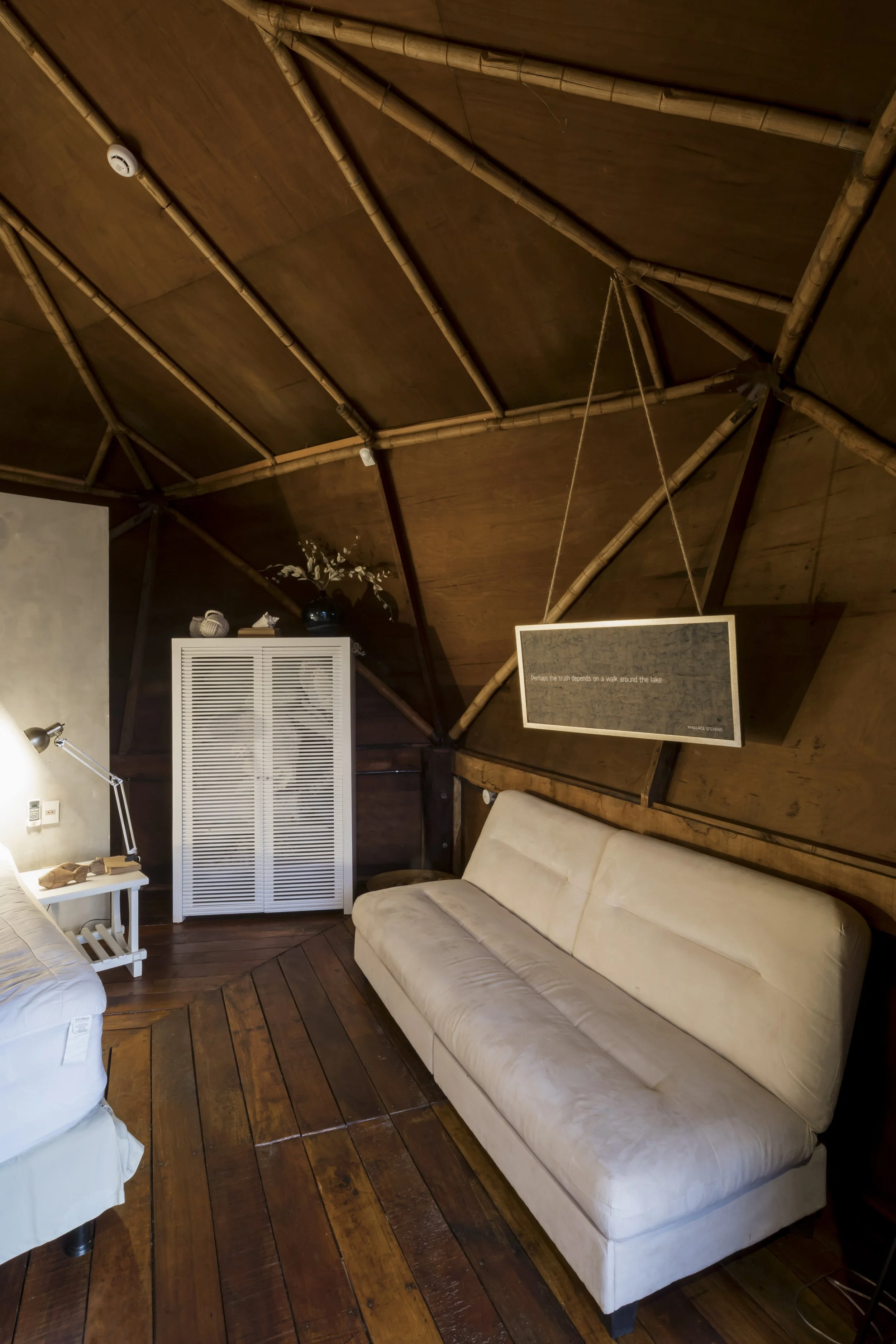 PRO ARQUITECTURA PARAGUAY architecture design PROSA
Sala de estar con sofá beige, lámpara de lectura, mueble blanco con puertas enrollables y un cuadro colgado en la pared de madera.