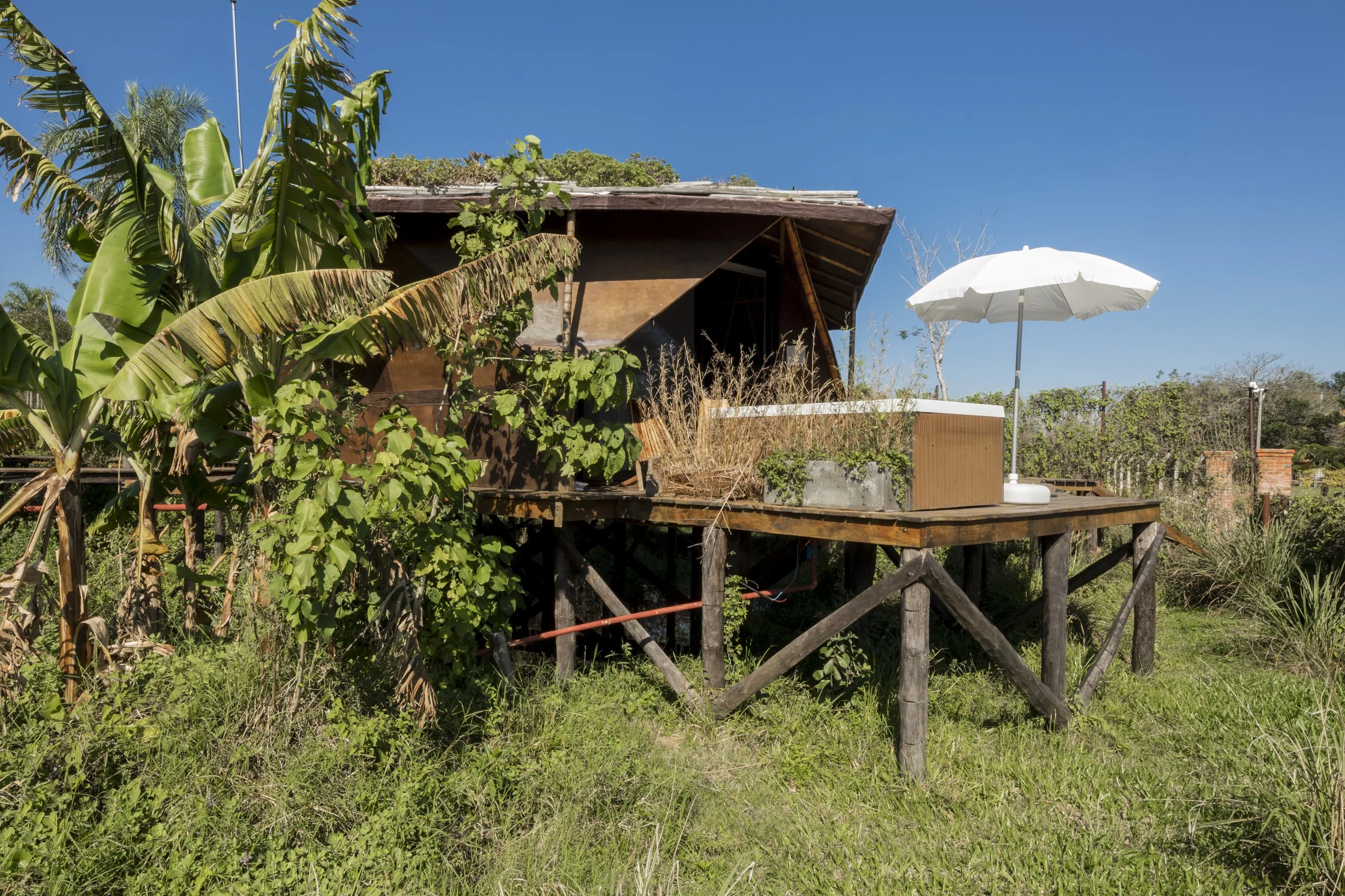 PRO ARQUITECTURA PARAGUAY architecture design PROSA
Casa en altura rodeada de vegetación con un paraguas blanco en la terraza