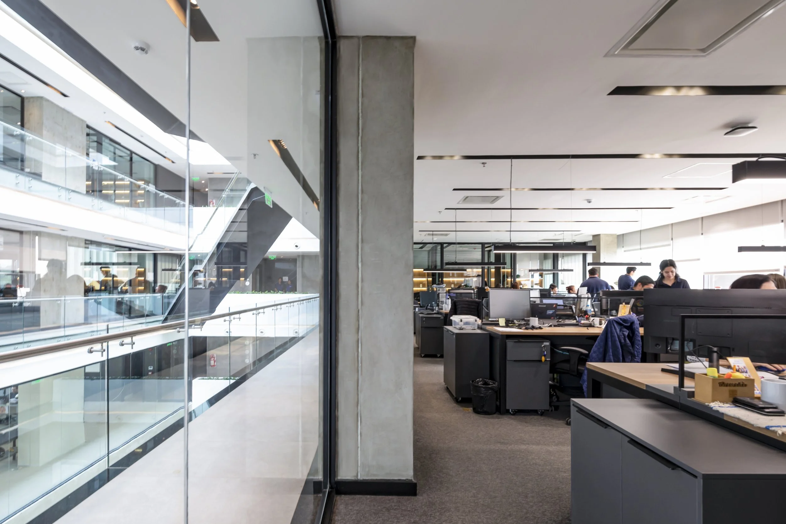 PRO ARQUITECTURA PARAGUAY architecture design PROSA
Imagen de una oficina moderna con varias mesas y computadoras, y empleados trabajando, vista desde un lado con un muro de vidrio y ventanas grandes que permiten la entrada de luz natural.