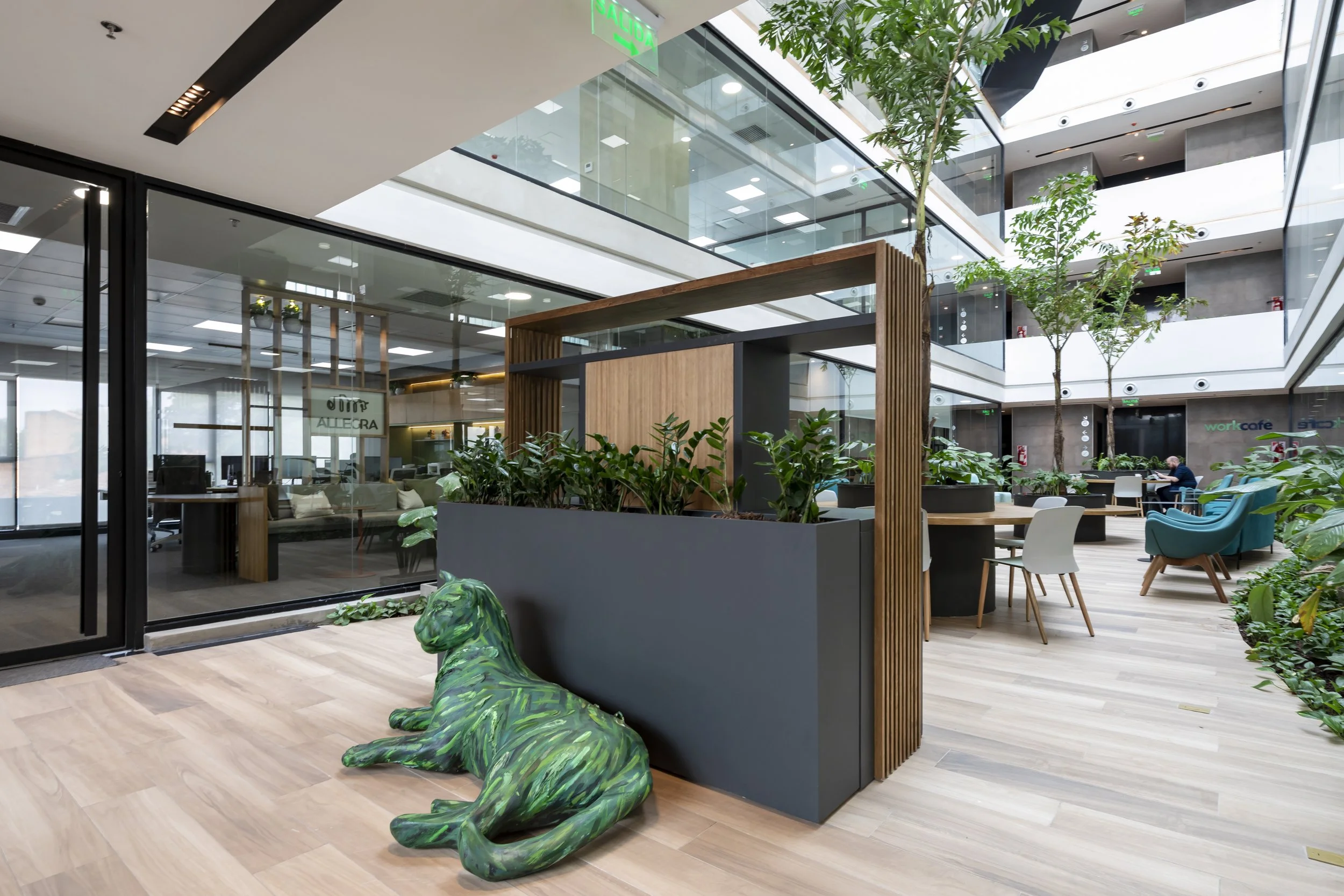 PRO ARQUITECTURA PARAGUAY architecture design PROSA
Interior moderno de oficina con áreas verdes, mobiliario de colores y una escultura de un perro en el primer plano.