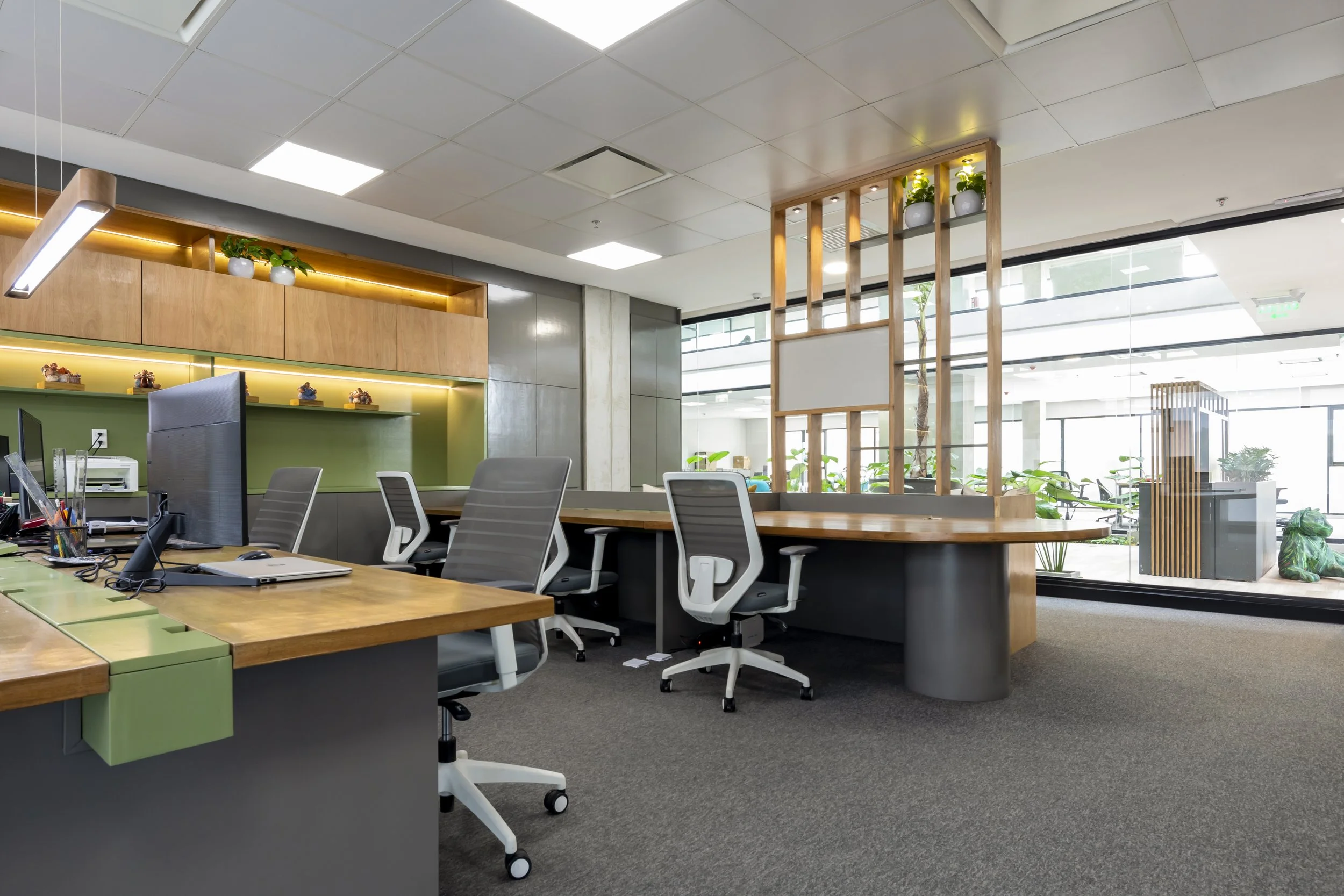 PRO ARQUITECTURA PARAGUAY architecture design PROSA
Oficina moderna con escritorios de madera, sillas ergonómicas, y una pared de cristales que permite vista a un área con plantas y muebles.