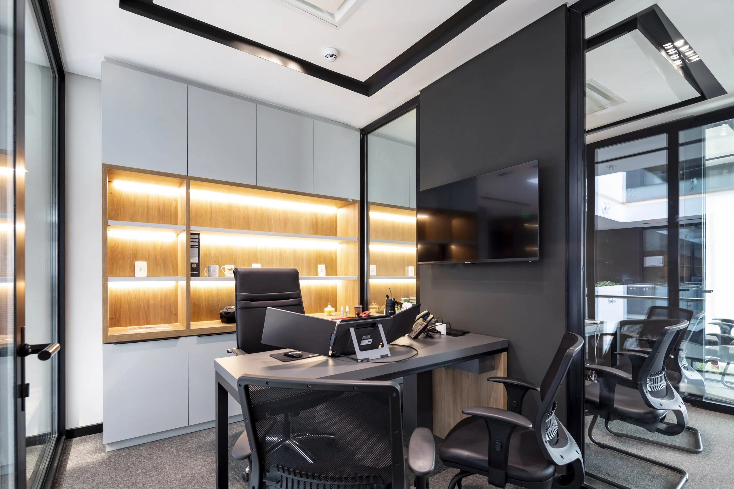 PRO ARQUITECTURA PARAGUAY architecture design PROSA
Despacho de oficina moderna con mesa de trabajo, sillas ergonómicas, estantería con luz led, pantalla montada en la pared y ventanas de cristales con vista al exterior