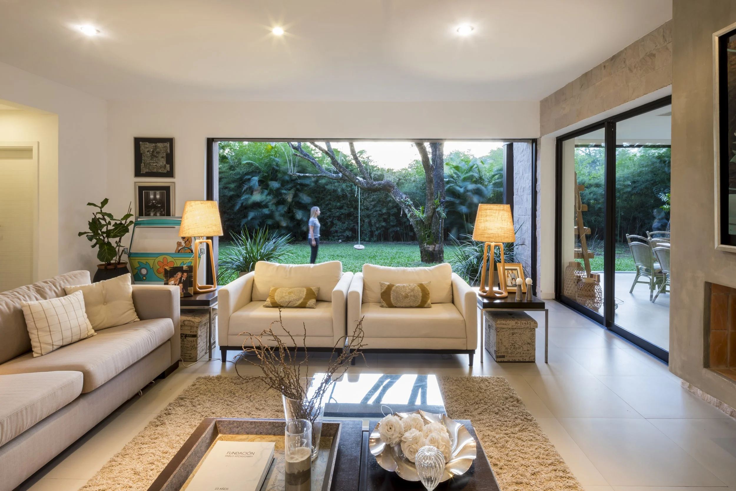 PRO ARQUITECTURA PARAGUAY architecture design PROSA
Sala de estar moderna con sillones blancos, lámparas de mesa y vista al jardín por paredes de cristal