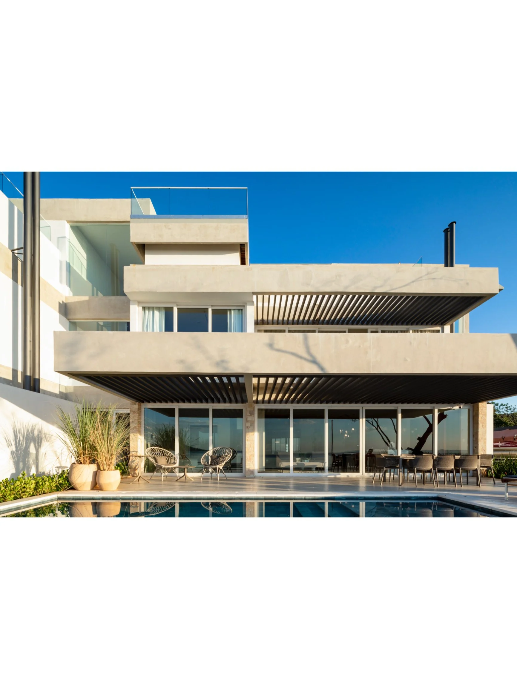 PRO ARQUITECTURA PARAGUAY architecture design PROSA
Edificio moderno con varias terrazas, gran ventana de vidrio, áreas de descanso y piscina en primer plano.