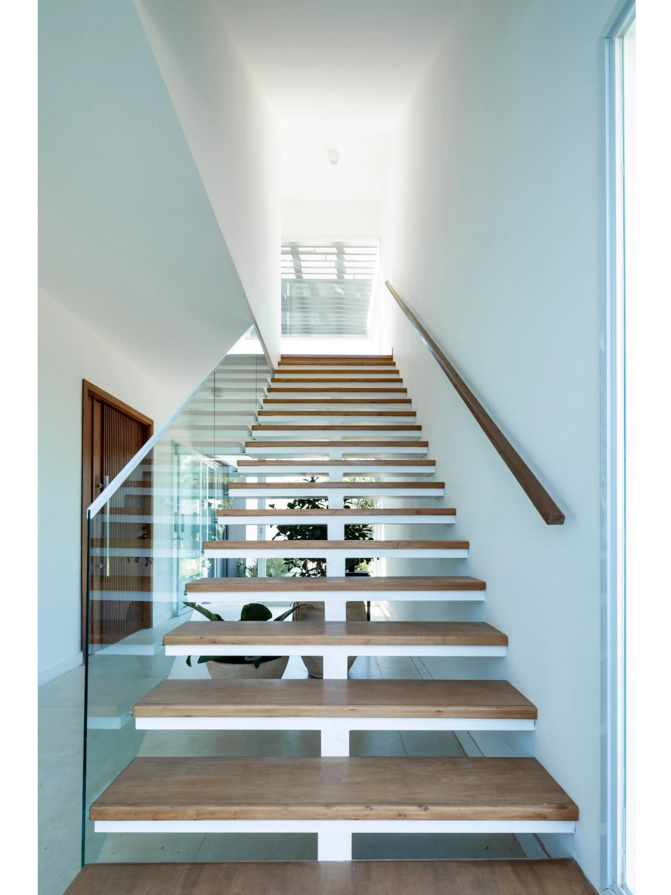 PRO ARQUITECTURA PARAGUAY architecture design PROSA
Escalera moderna con peldaños de madera y barandilla de cristal en interior bien iluminado.