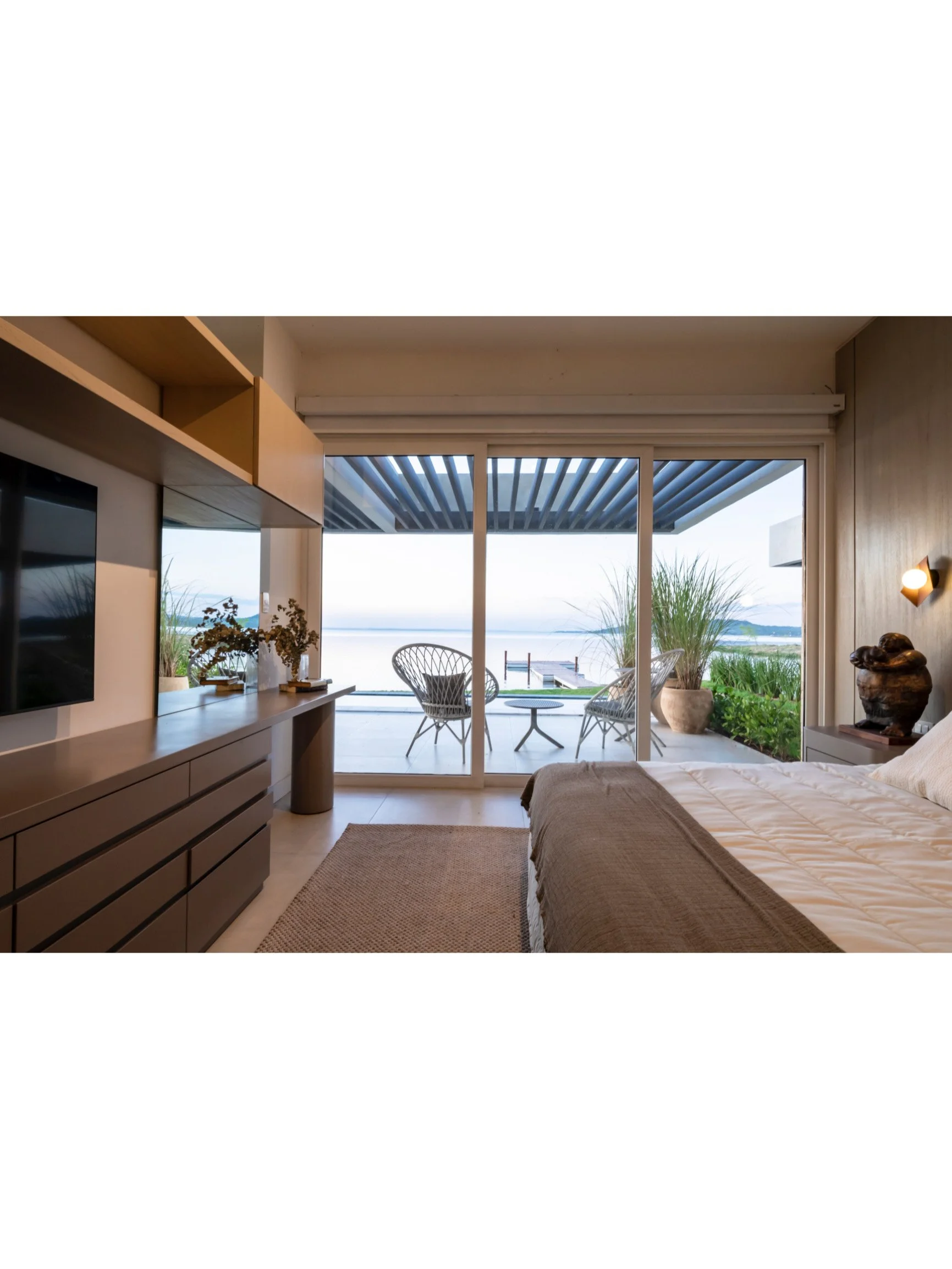 PRO ARQUITECTURA PARAGUAY architecture design PROSA
Habitación con vista al mar, cama, televisión, muebles de madera y balcón con sillones y plantas