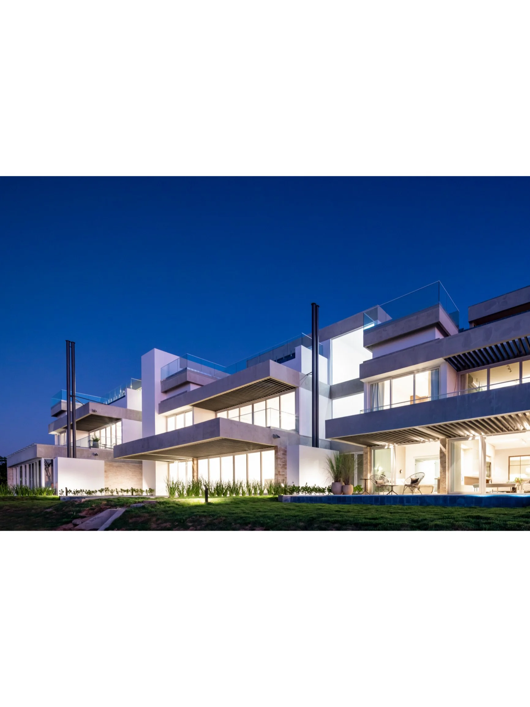 PRO ARQUITECTURA PARAGUAY architecture design PROSA
Casa moderna de varios niveles con grandes ventanales, balcones y áreas exteriores iluminadas durante la noche.