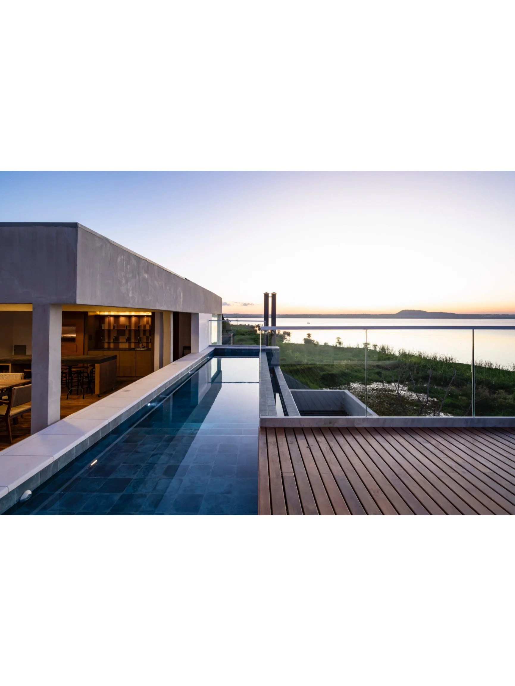 PRO ARQUITECTURA PARAGUAY architecture design PROSA
Vista de una terraza con una piscina y vista al cuerpo de agua y horizonte al atardecer en un entorno moderno y elegante