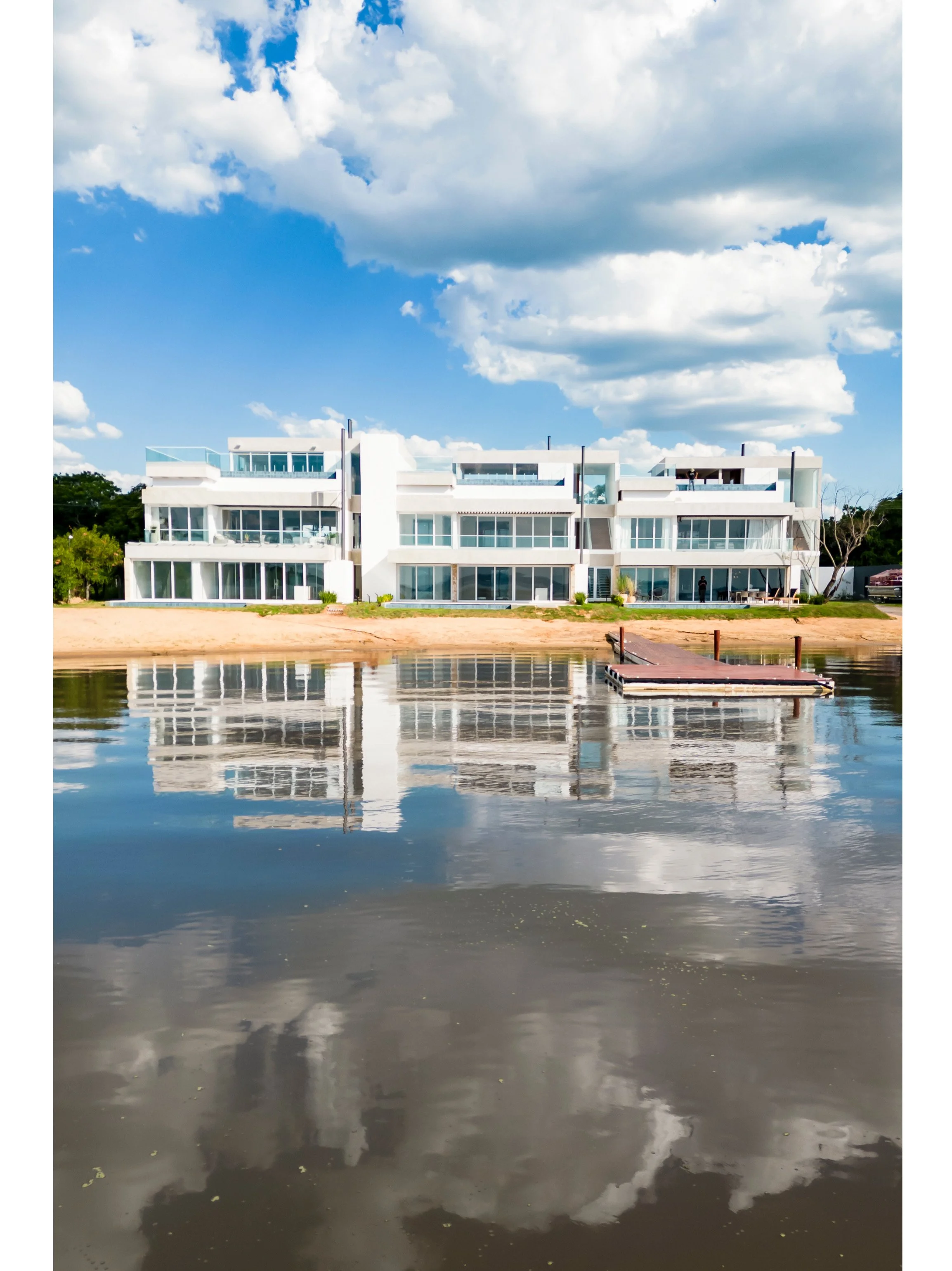 PRO ARQUITECTURA PARAGUAY architecture design PROSA
Edificio moderno blanco junto a un cuerpo de agua con reflejo de las nubes y el edificio.