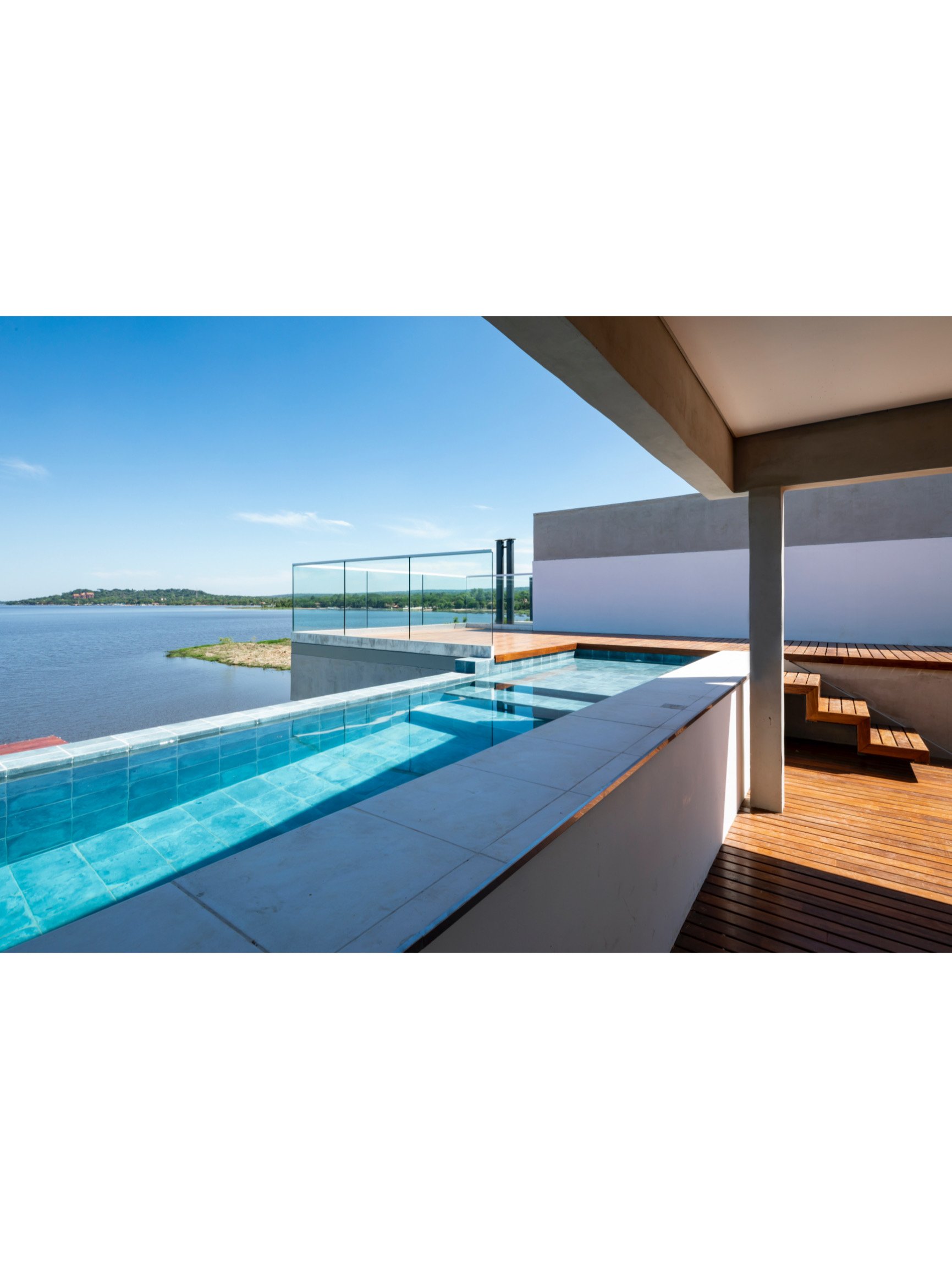 PRO ARQUITECTURA PARAGUAY architecture design PROSA
Vista de una piscina y balcón con vista a un lago bajo un cielo despejado.