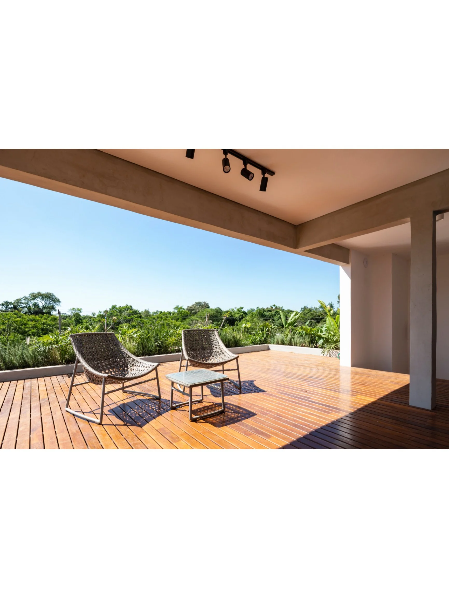 PRO ARQUITECTURA PARAGUAY architecture design PROSA
Terraza con dos sillas de mimbre y una mesa, rodeada de vegetación y con cielo despejado.