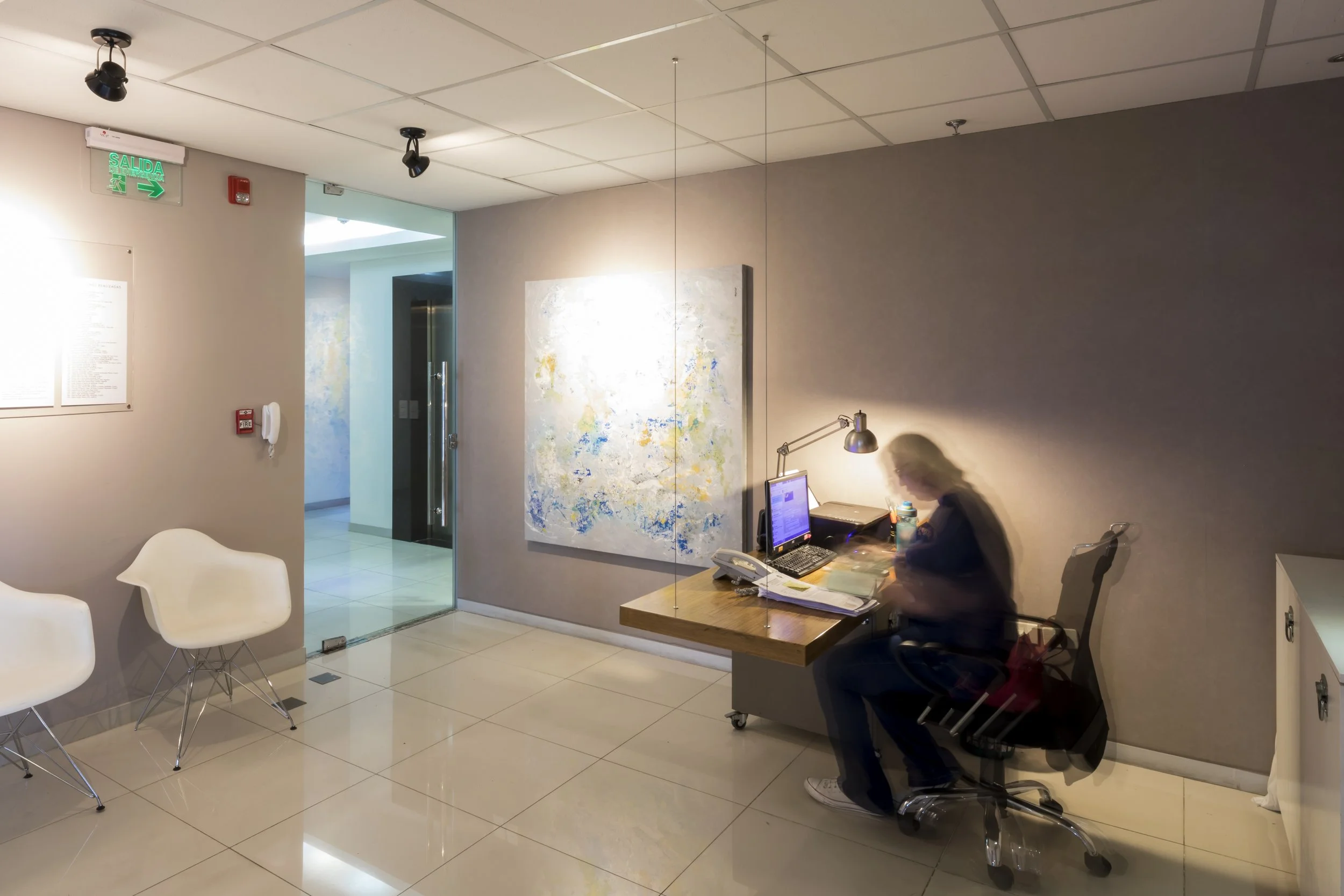 PRO ARQUITECTURA PARAGUAY architecture design PROSA
Recepcionista sentada en su escritorio en un lobby con silla blanca y una pintura abstracta en la pared.