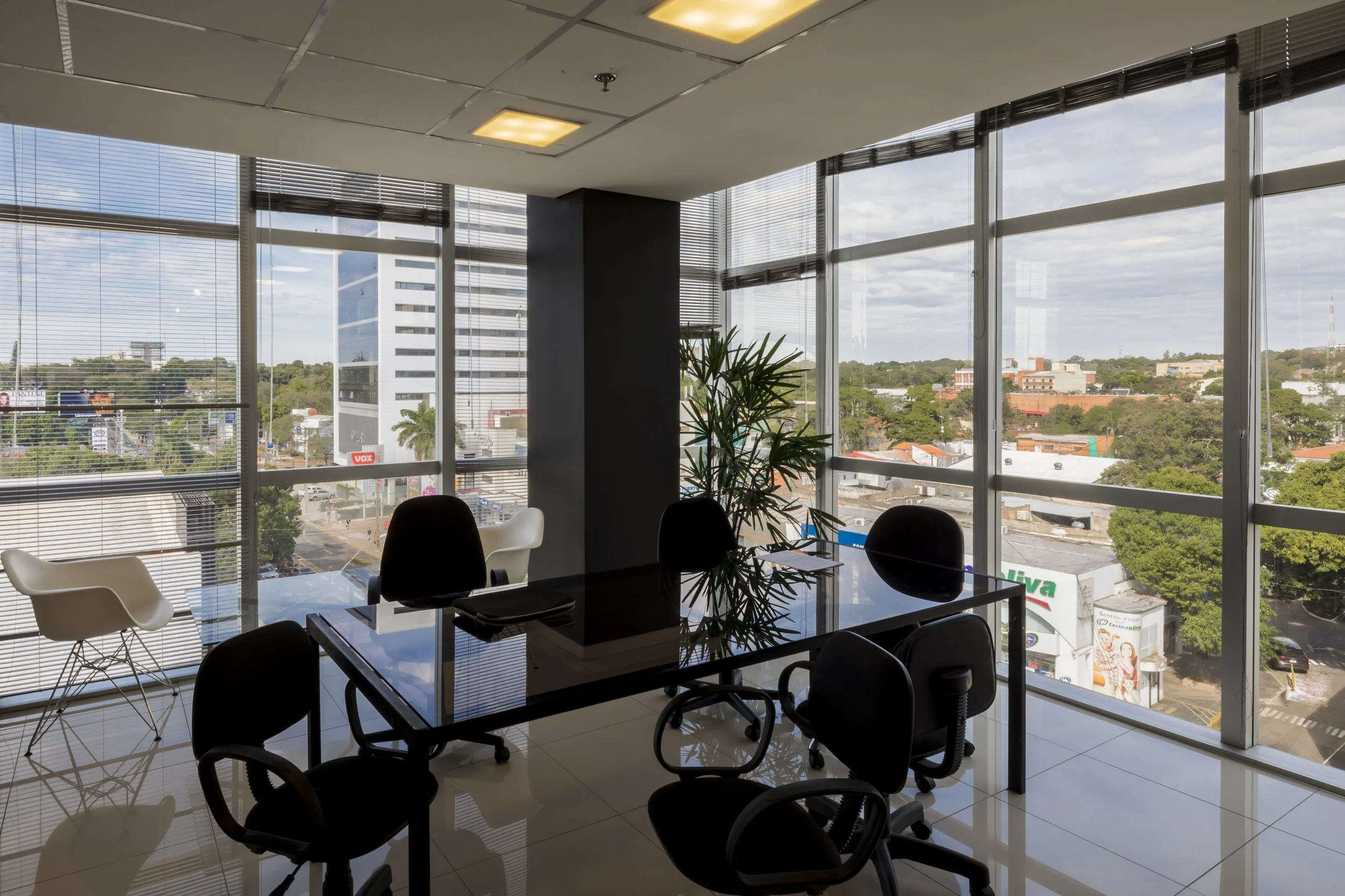 PRO ARQUITECTURA PARAGUAY architecture design PROSA
Sala de reuniones con mesas y sillas frente a ventanas panorámicas que muestran el paisaje urbano y un cielo nublado.