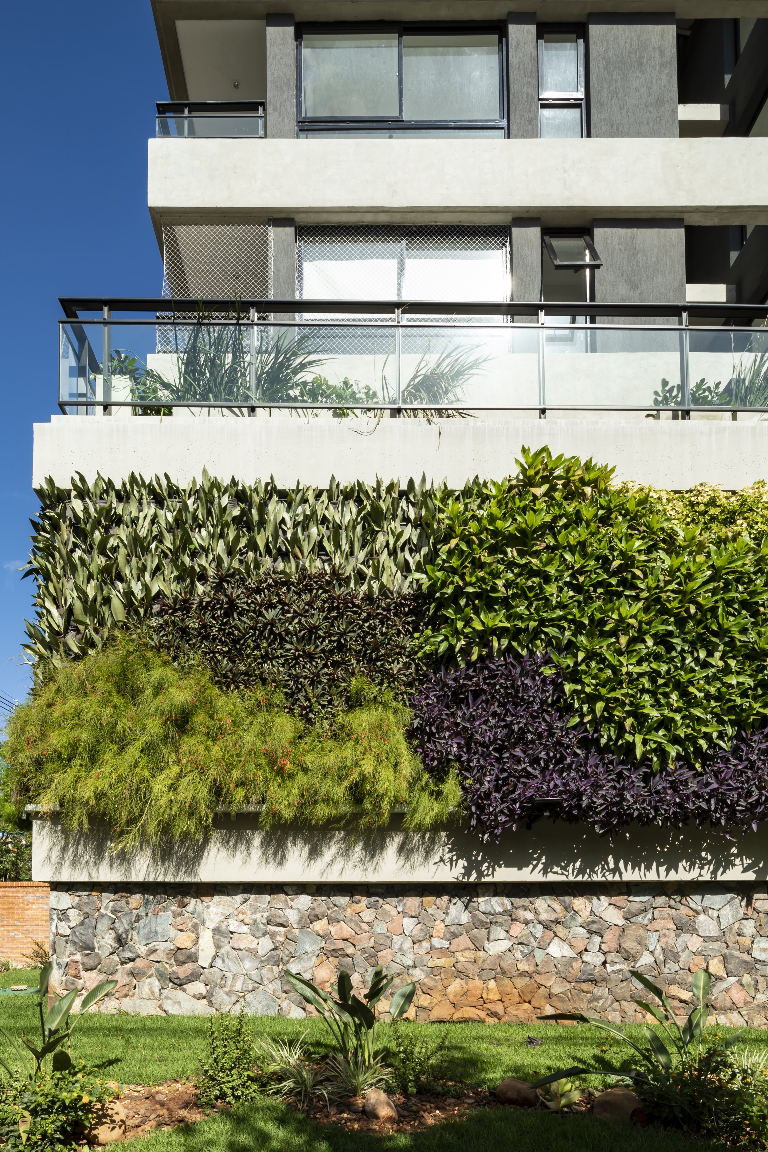Edificio moderno con fachada decorada con plantas verdes y arbustos.