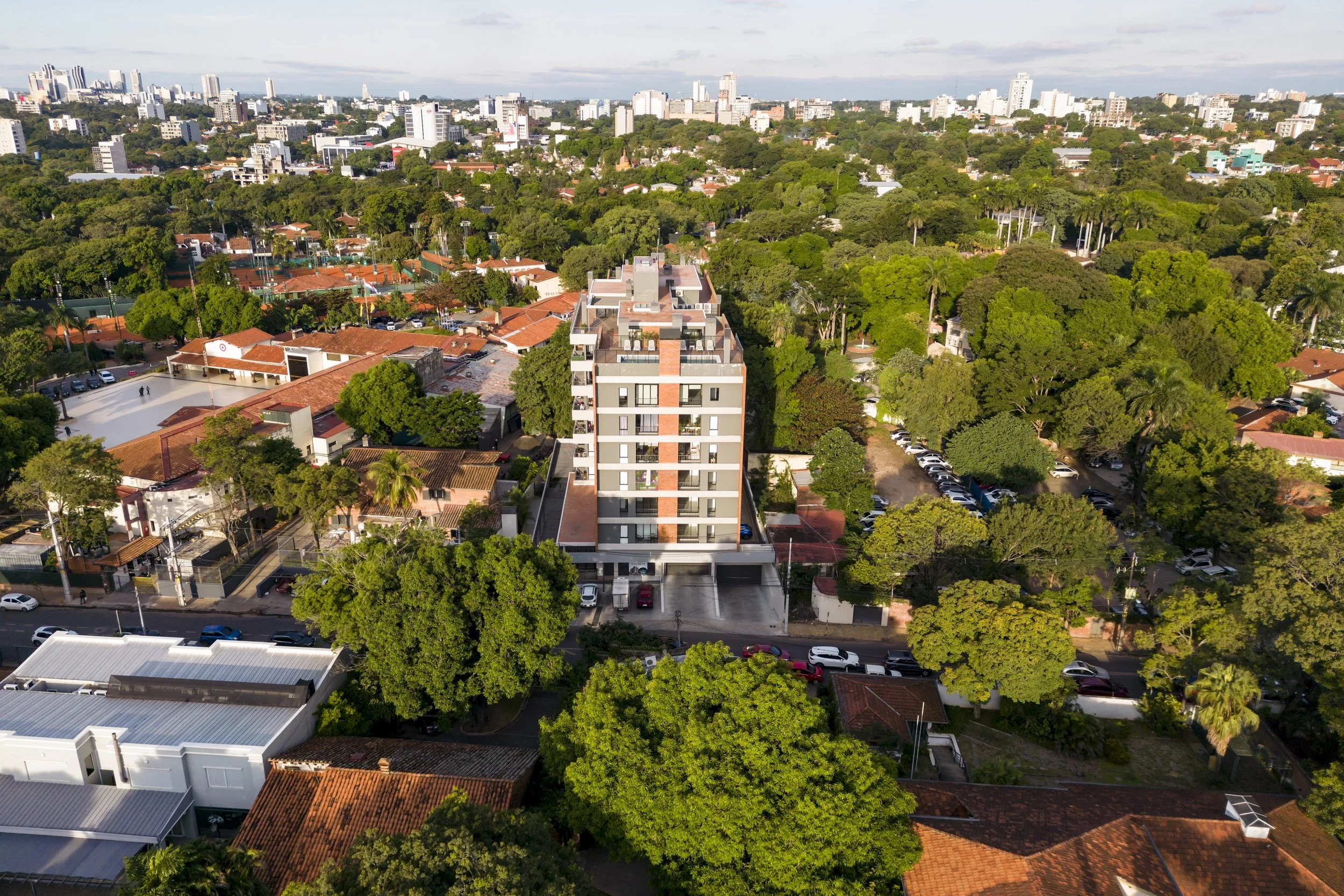	
PRO ARQUITECTURA PARAGUAY architecture design PROSA
Vista aérea de una ciudad con muchos árboles, edificios y casas, incluyendo un edificio moderno de varios pisos en el centro.