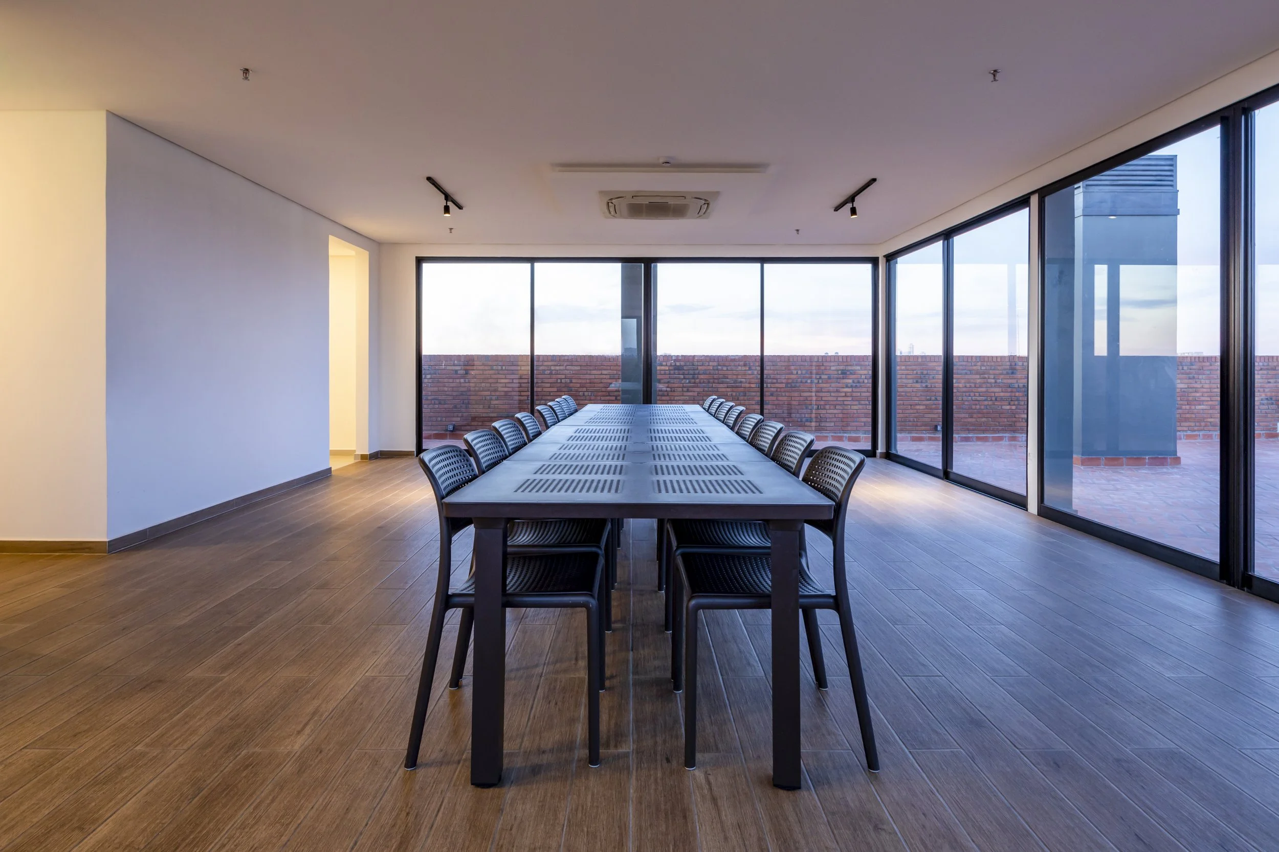 	
PRO ARQUITECTURA PARAGUAY architecture design PROSA
Sala de reuniones con una mesa larga y sillas negras, grandes ventanas de cristal y vista a un muro de ladrillos exteriores.