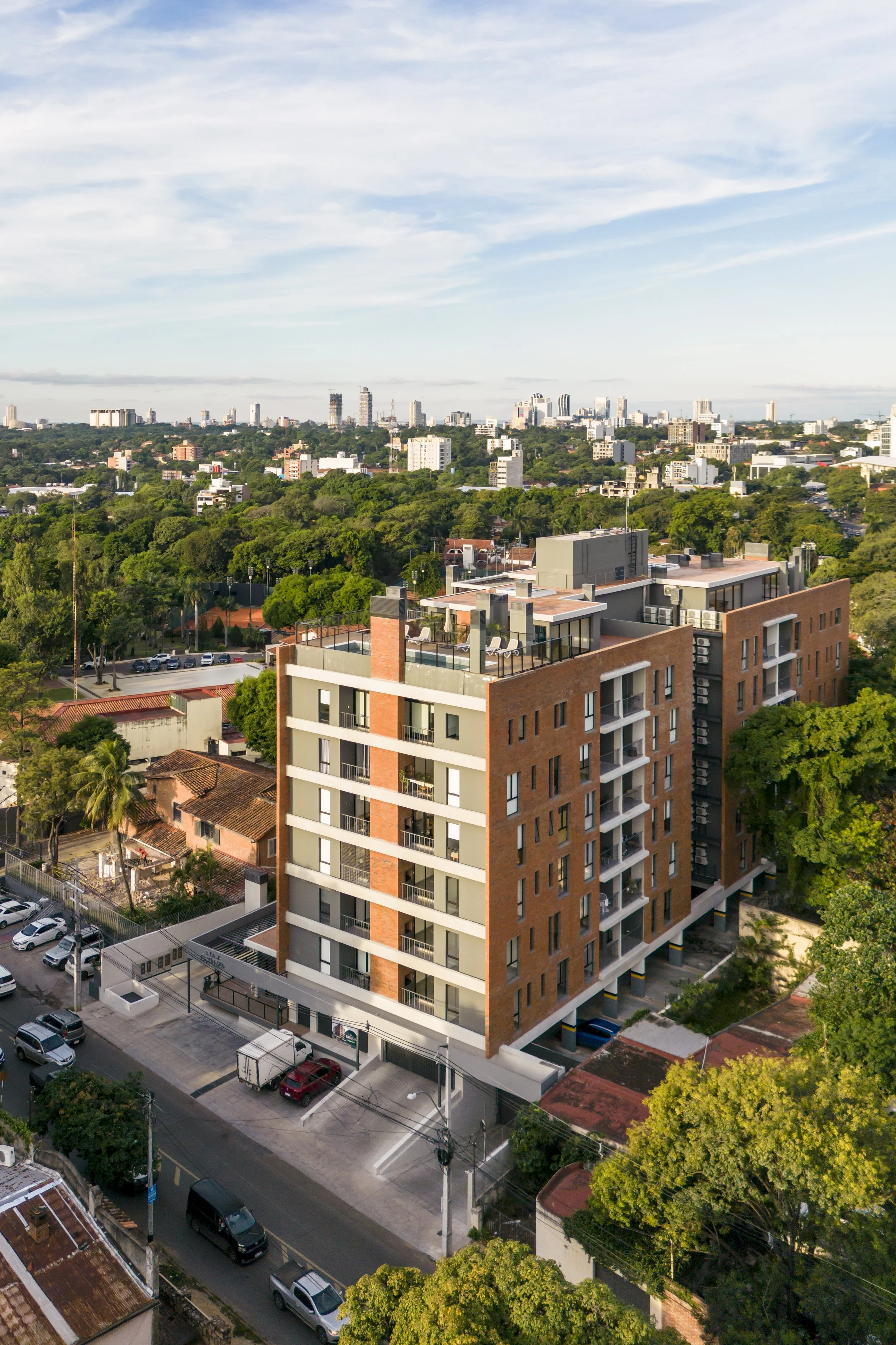 	
PRO ARQUITECTURA PARAGUAY architecture design PROSA
Edificio moderno en una ciudad con muchas áreas verdes y otros edificios en el fondo, visto desde arriba.