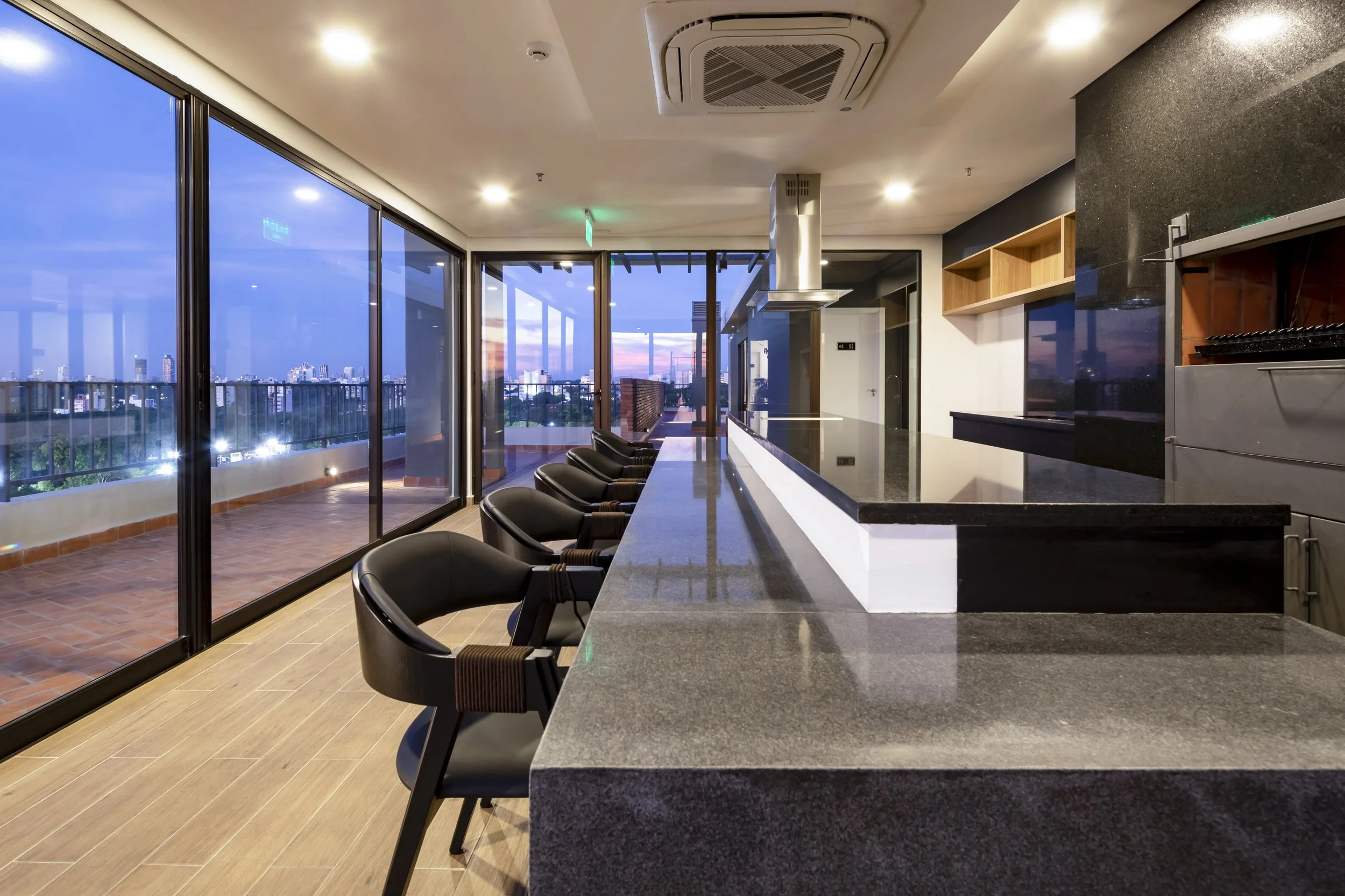 	
PRO ARQUITECTURA PARAGUAY architecture design PROSA
Bar con sillas negras y encimera de granito con vista a una terraza y ciudad al atardecer