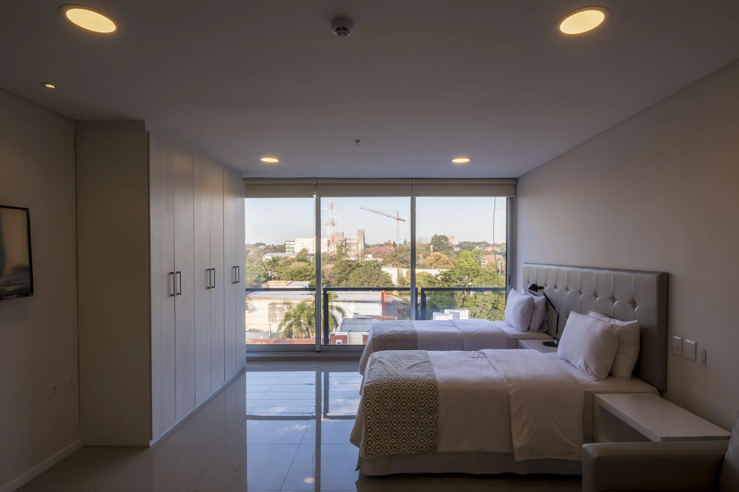 	
PRO ARQUITECTURA PARAGUAY architecture design PROSA
Habitación de hotel con dos camas y vista a la ciudad a través de grandes ventanas.