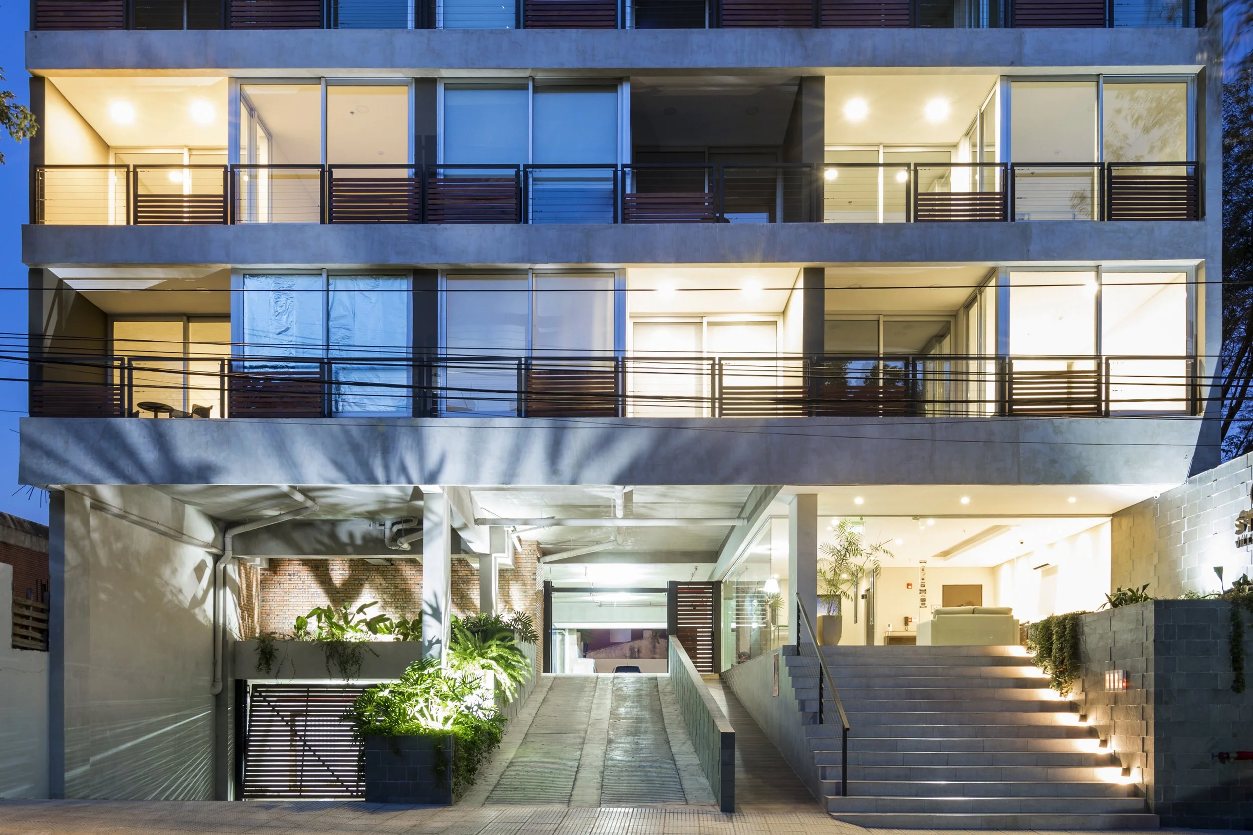	
PRO ARQUITECTURA PARAGUAY architecture design PROSA
Edificio moderno de varios pisos con balcones y amplio vestíbulo iluminado, entradas con escaleras y área de jardinería en el frente.