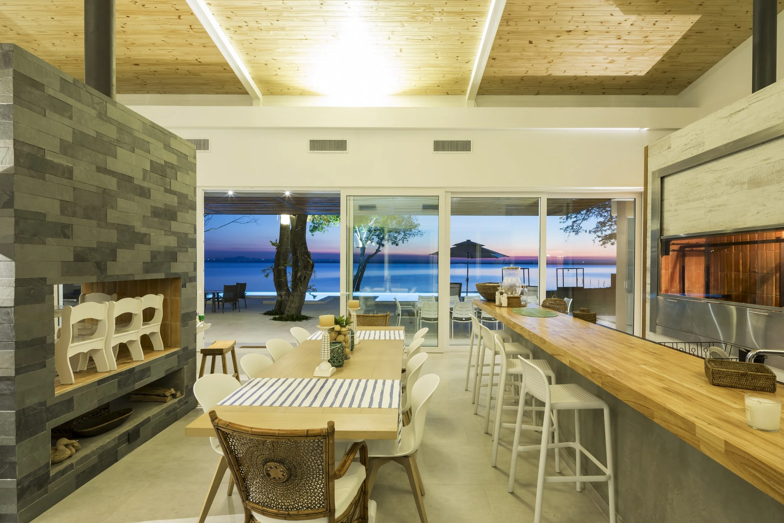 	
PRO ARQUITECTURA PARAGUAY architecture design PROSA
Interior de un restaurante con vista al mar, con mesas, sillas y barra de madera, en un ambiente iluminado y moderno.