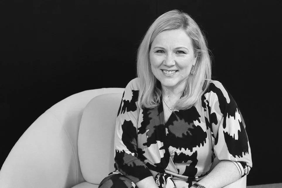 Elina Bono istuu sohvalla, taustalla musta seinä, kuva mustavalkoinen.