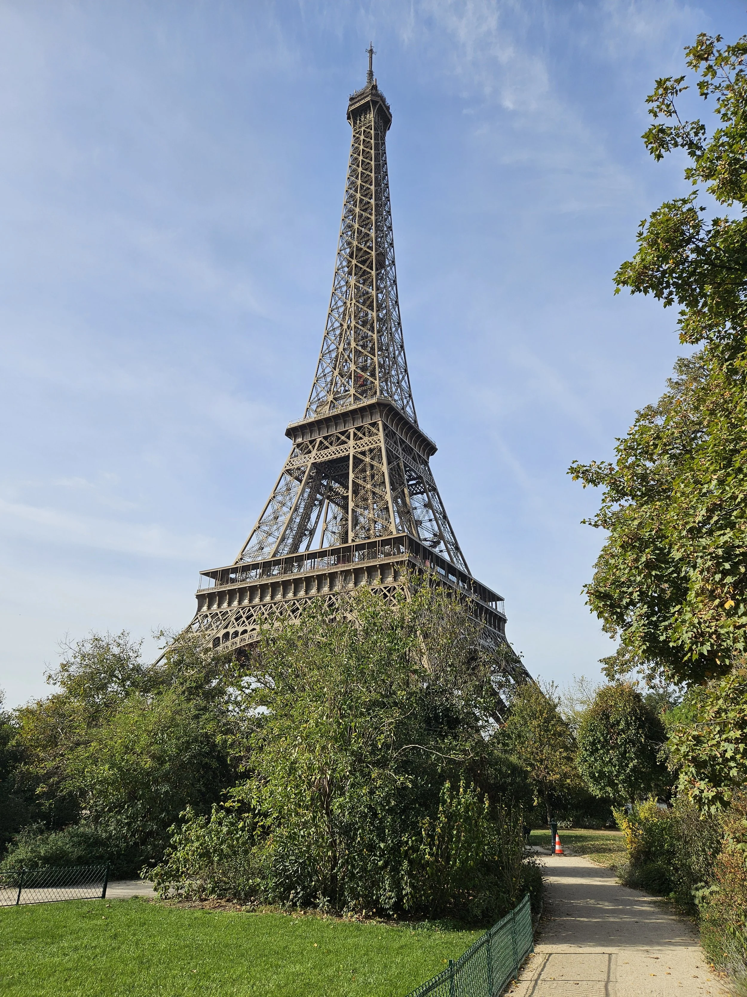 De Eiffel-toren in Parijs, omgeven door groen en een voetpad aan de rechterkant.